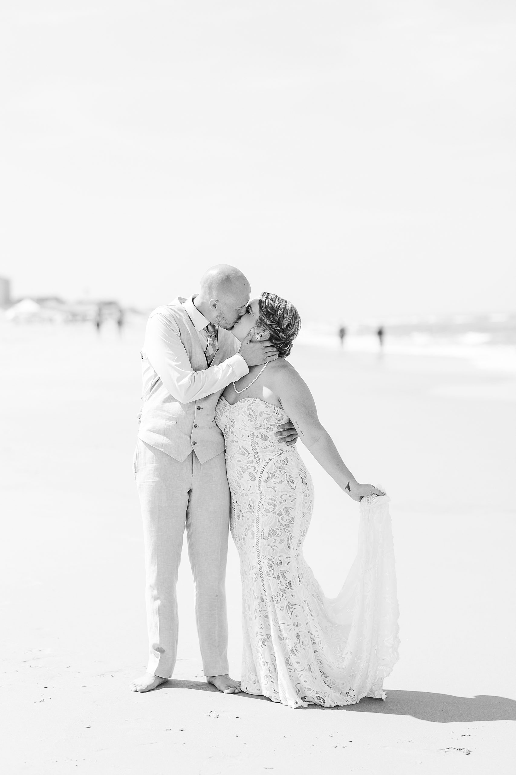 groom kisses bride on beach during OBX wedding photos