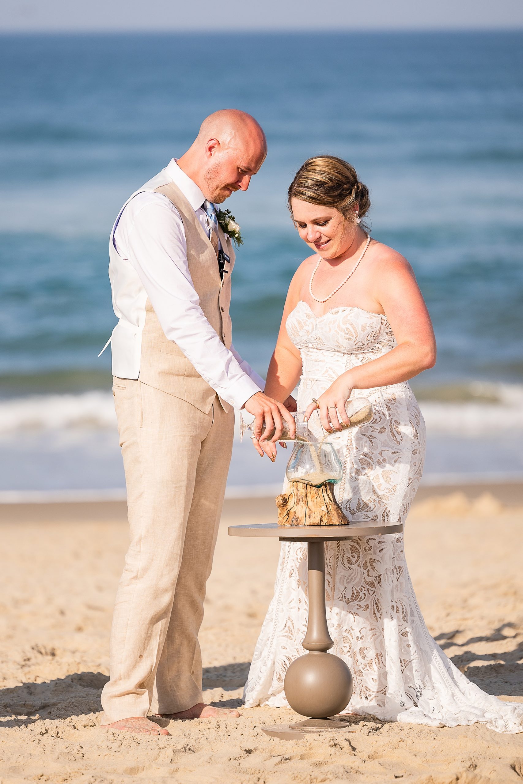couple pours sand together during OBX wedding ceremony on the beach