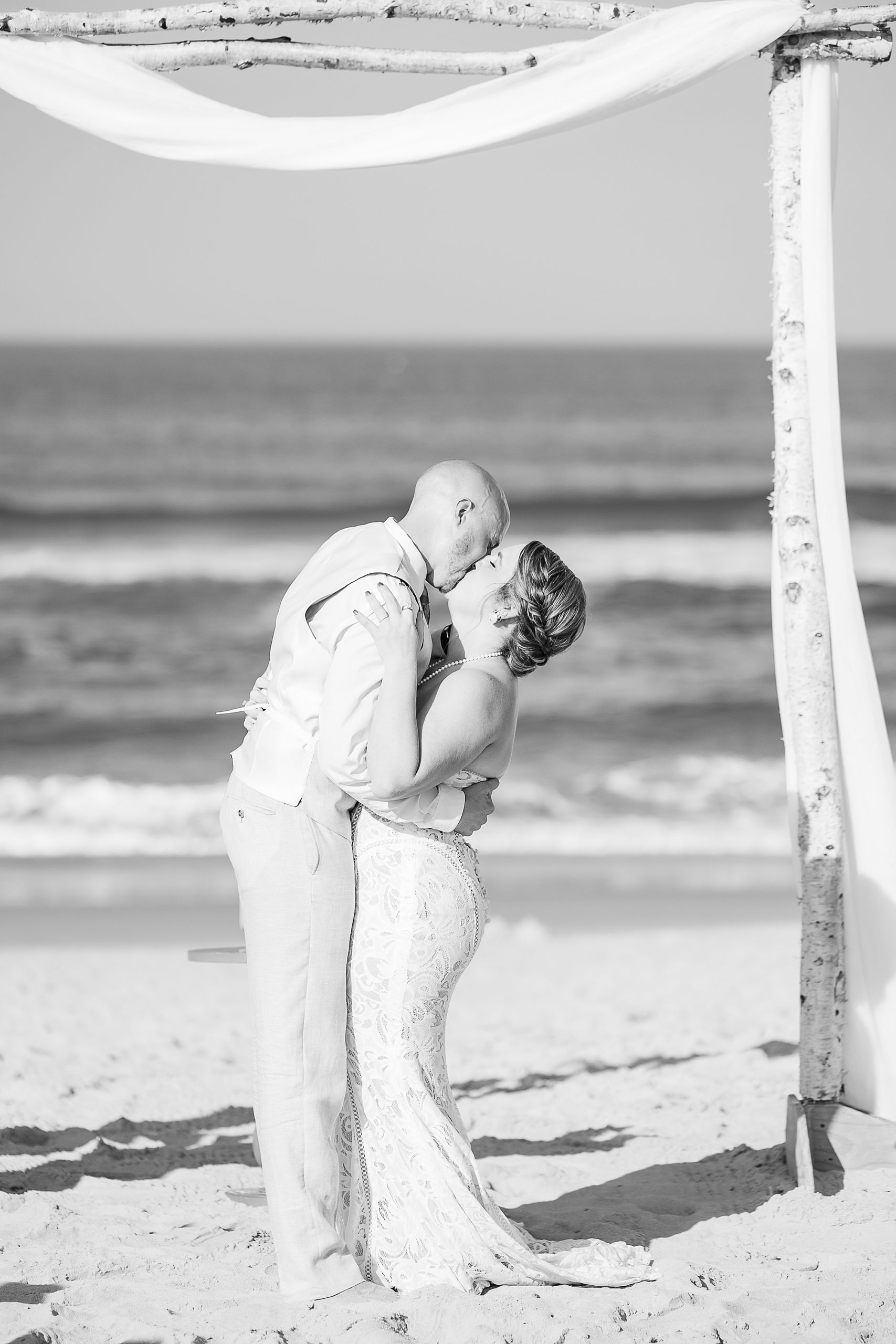 groom kisses bride during OBX wedding ceremony