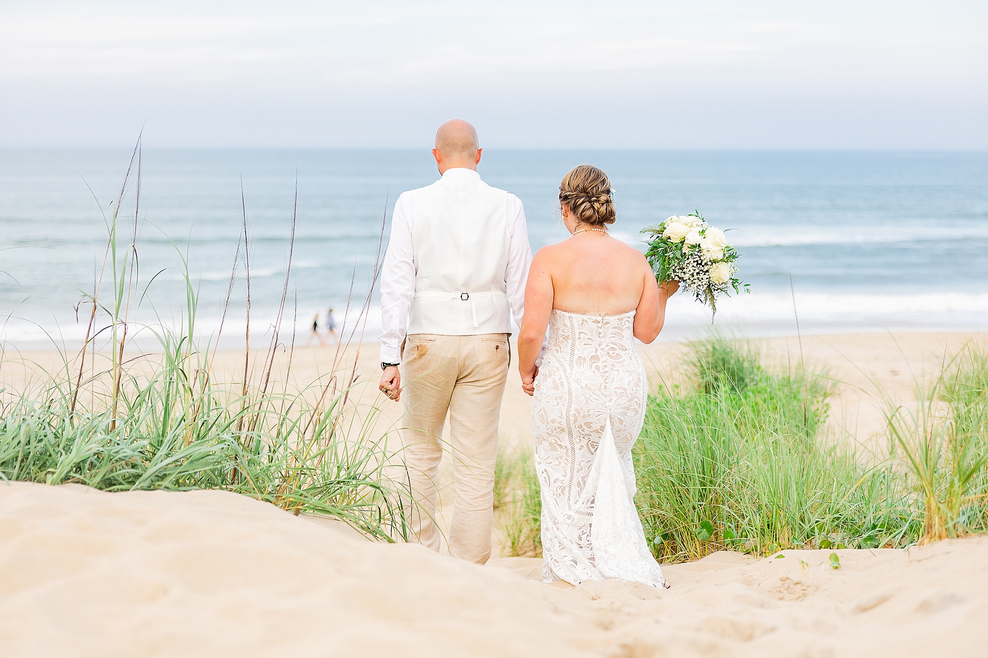 newlyweds walk onto beach at sunset for portraits 