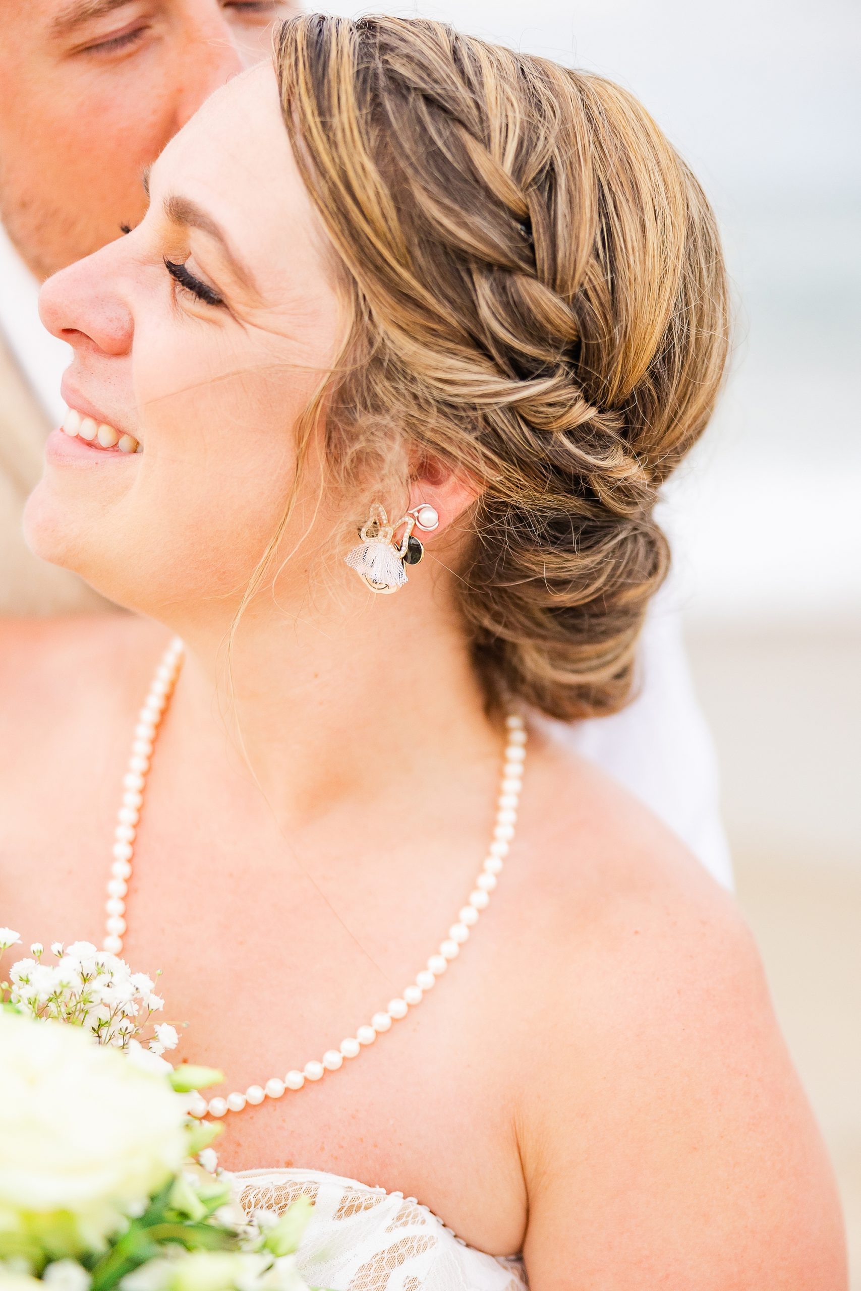 bride smiles while groom kisses her cheek showing off Minnie earrings