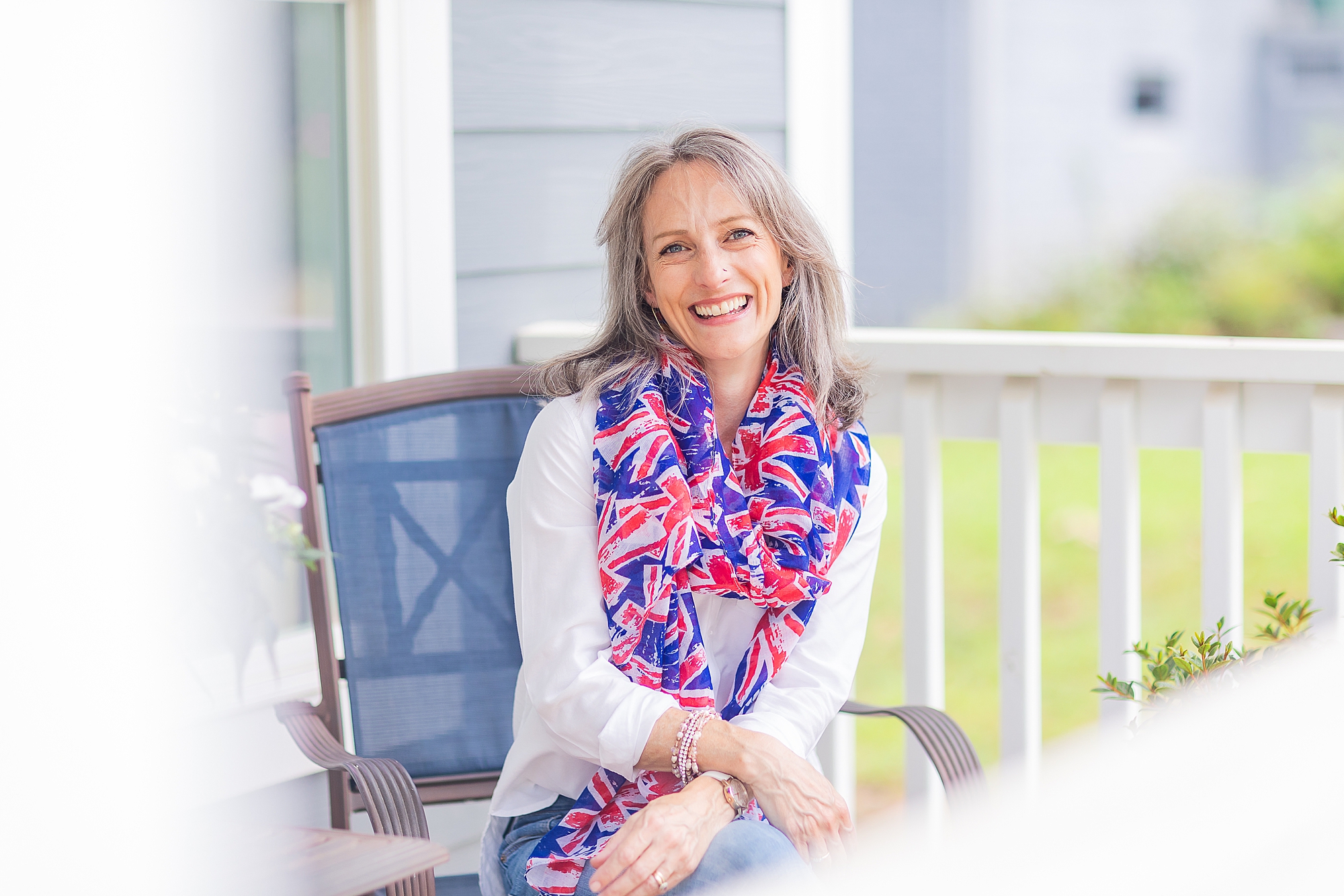 woman sits on front porch with scarf of UK flag 