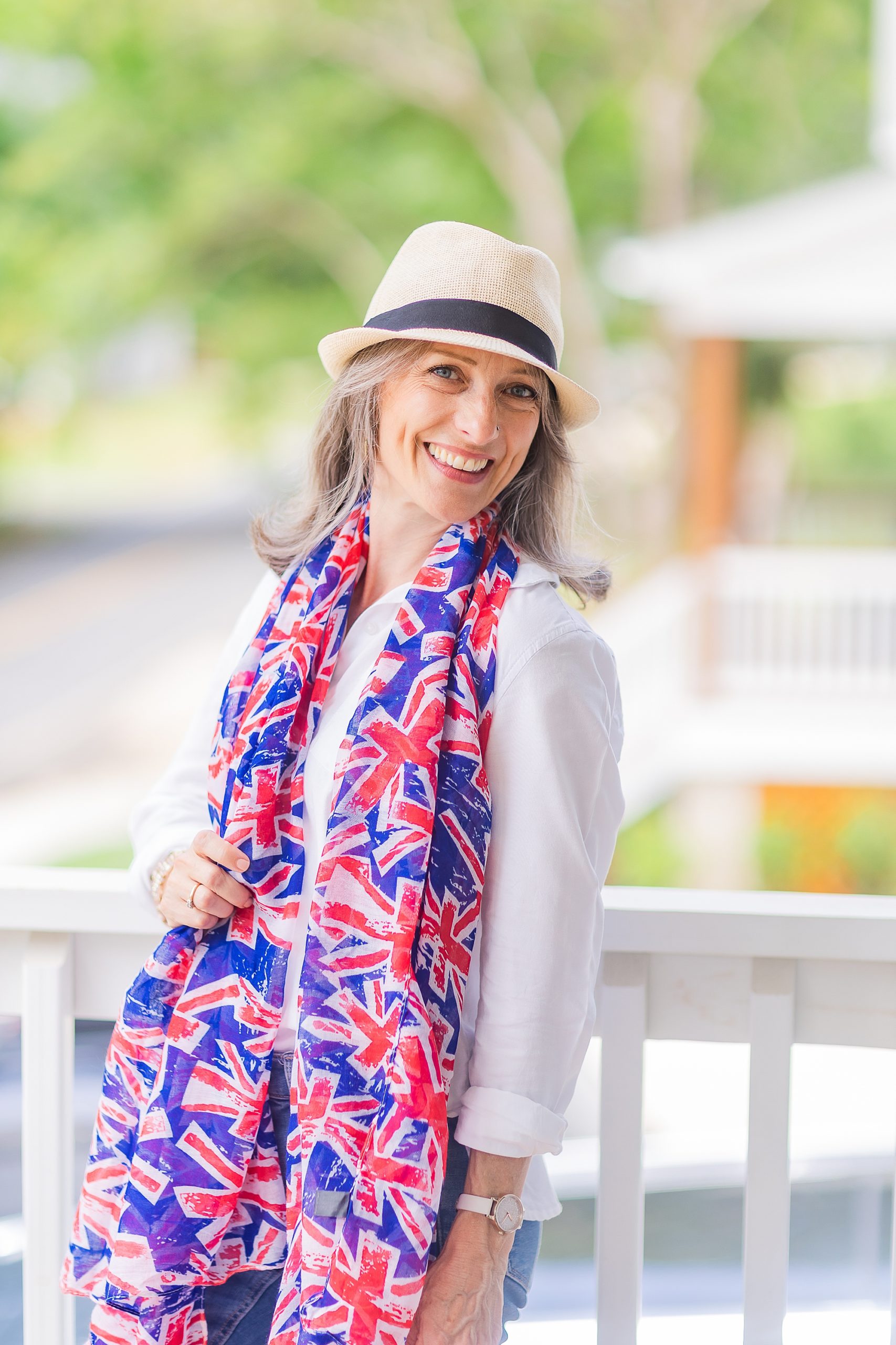 woman laughs with British flag scarf and hat on front porch