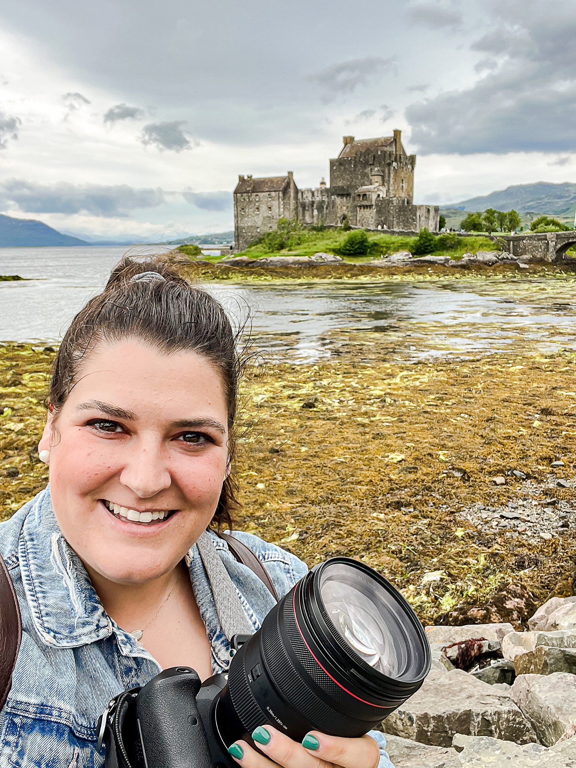woman poses in front of castle with camera in Scotland