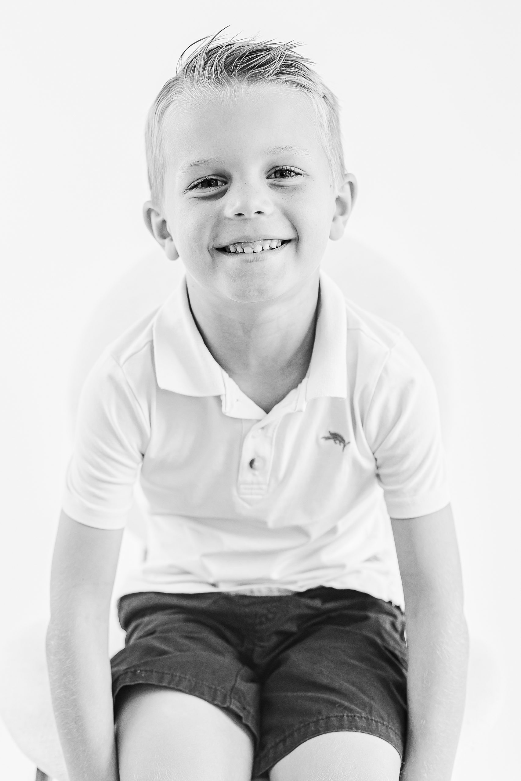 boy in white polo smiles during Charlotte Personality Portraits