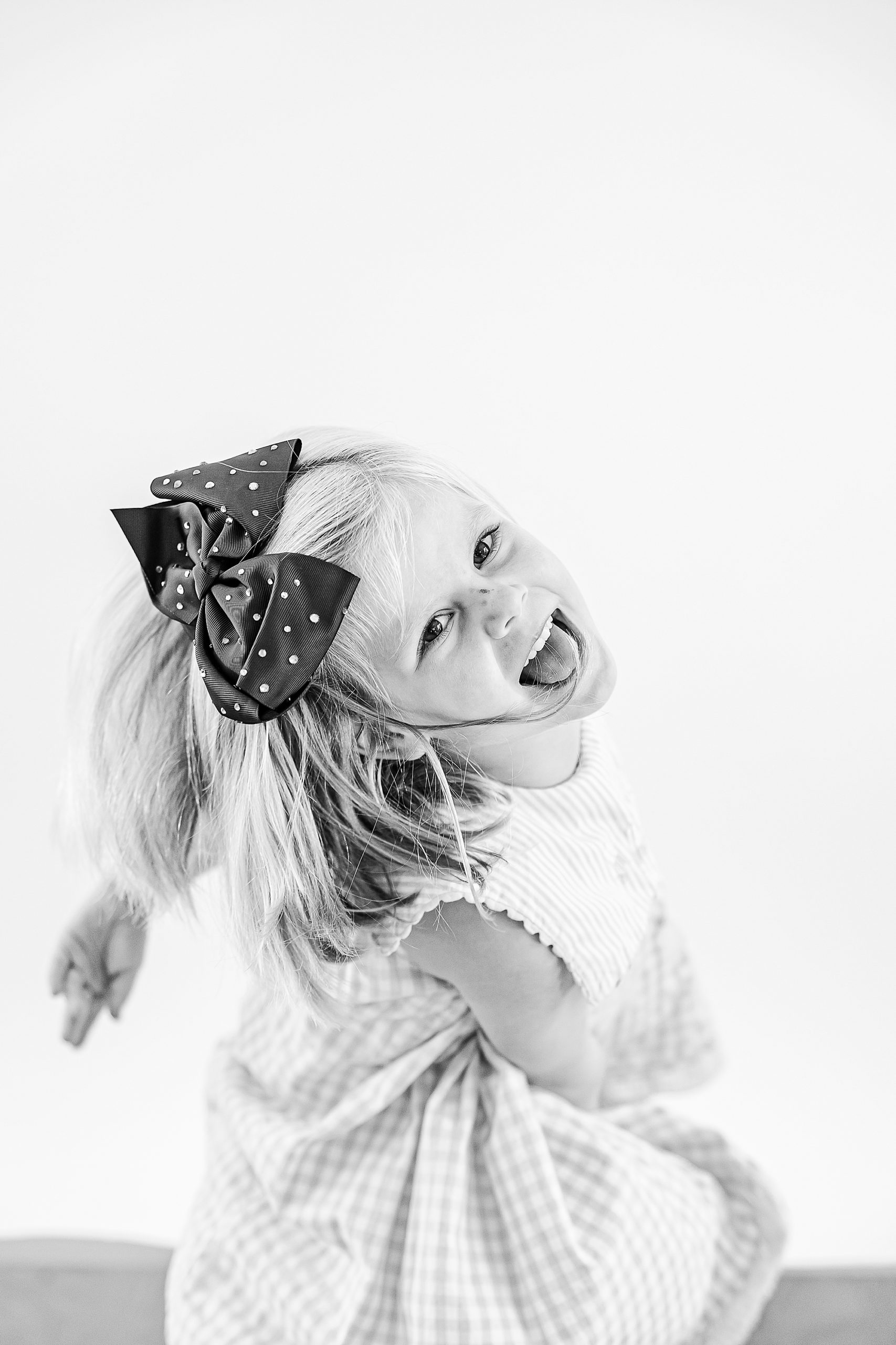 toddler with big bow laughs during NC studio portraits 