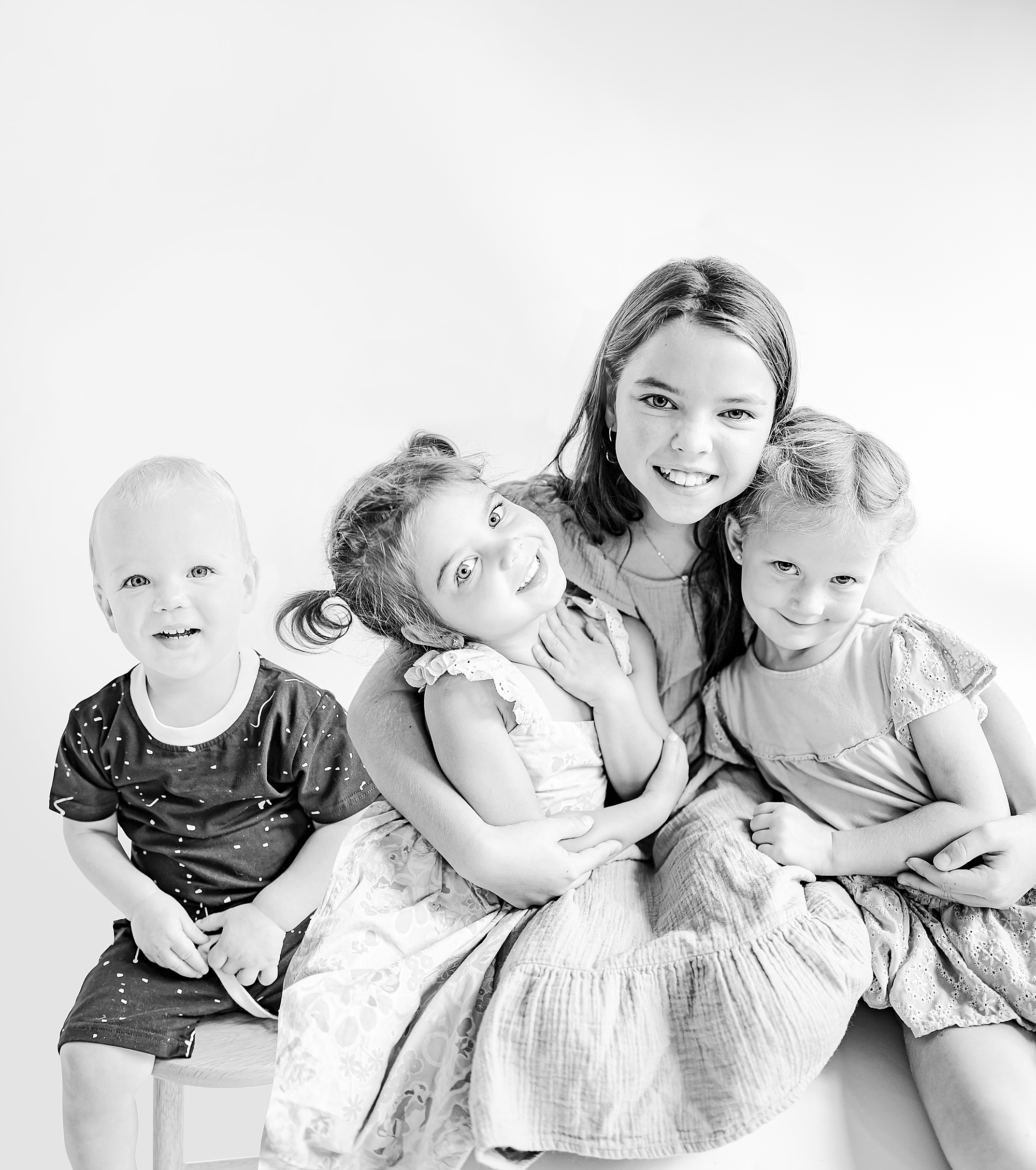 four siblings hug sitting in home studio during personality portraits