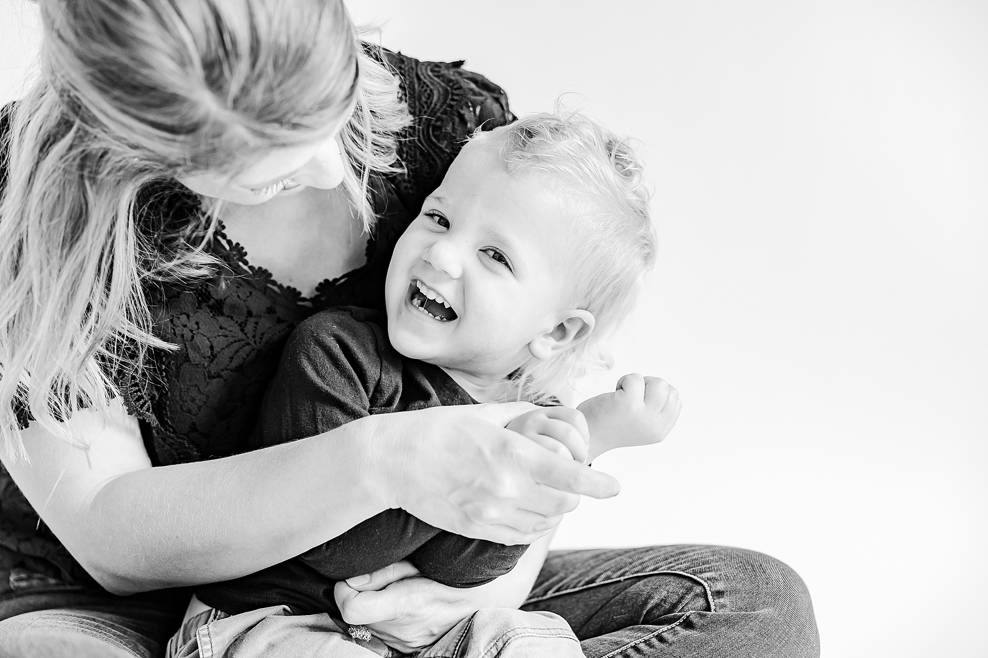 kid laughs with mom during studio portraits at home