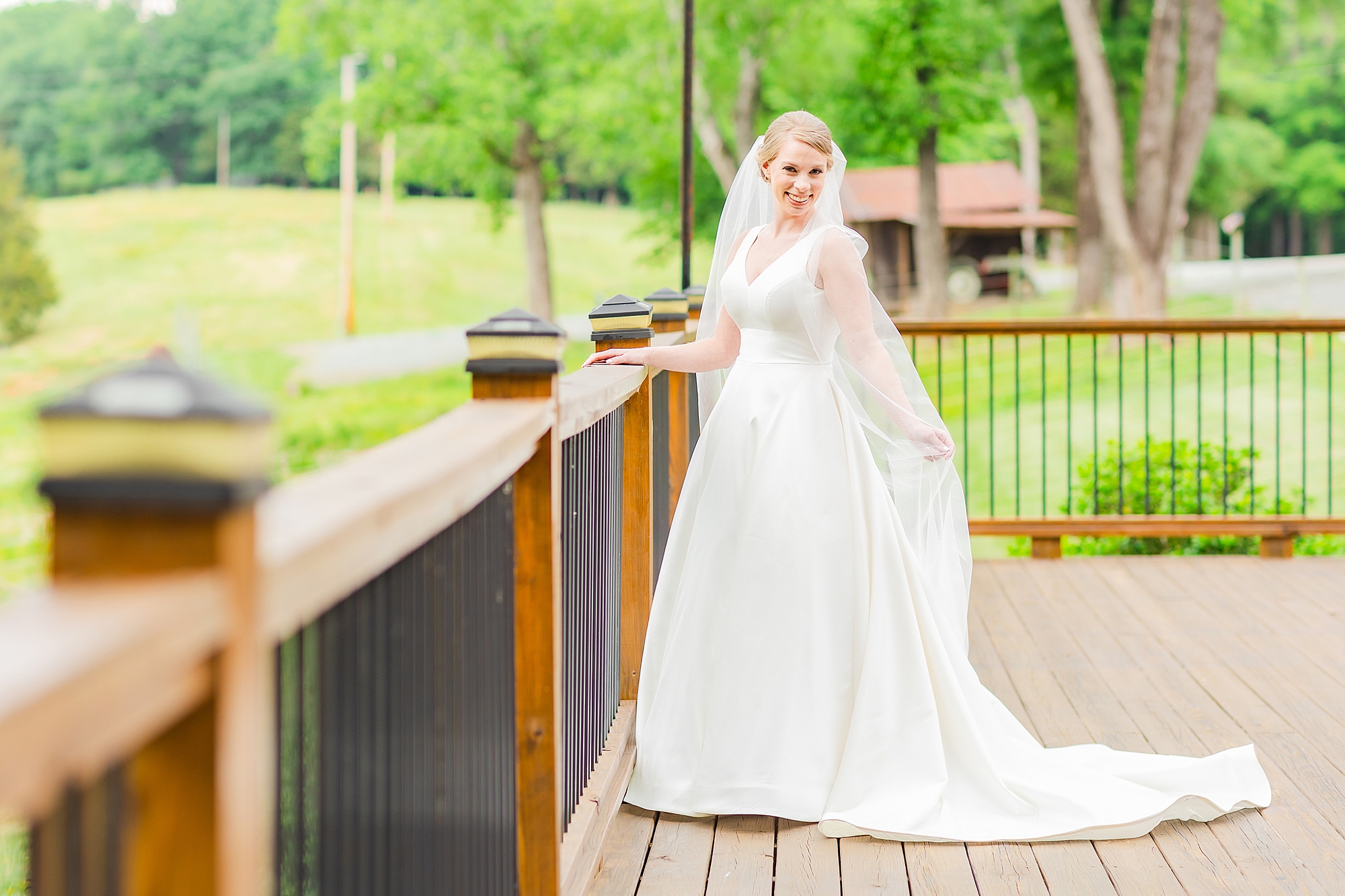 bride stands on patio at Old Homeplace Vineyards during bridal portraits with Charlotte wedding photographer 