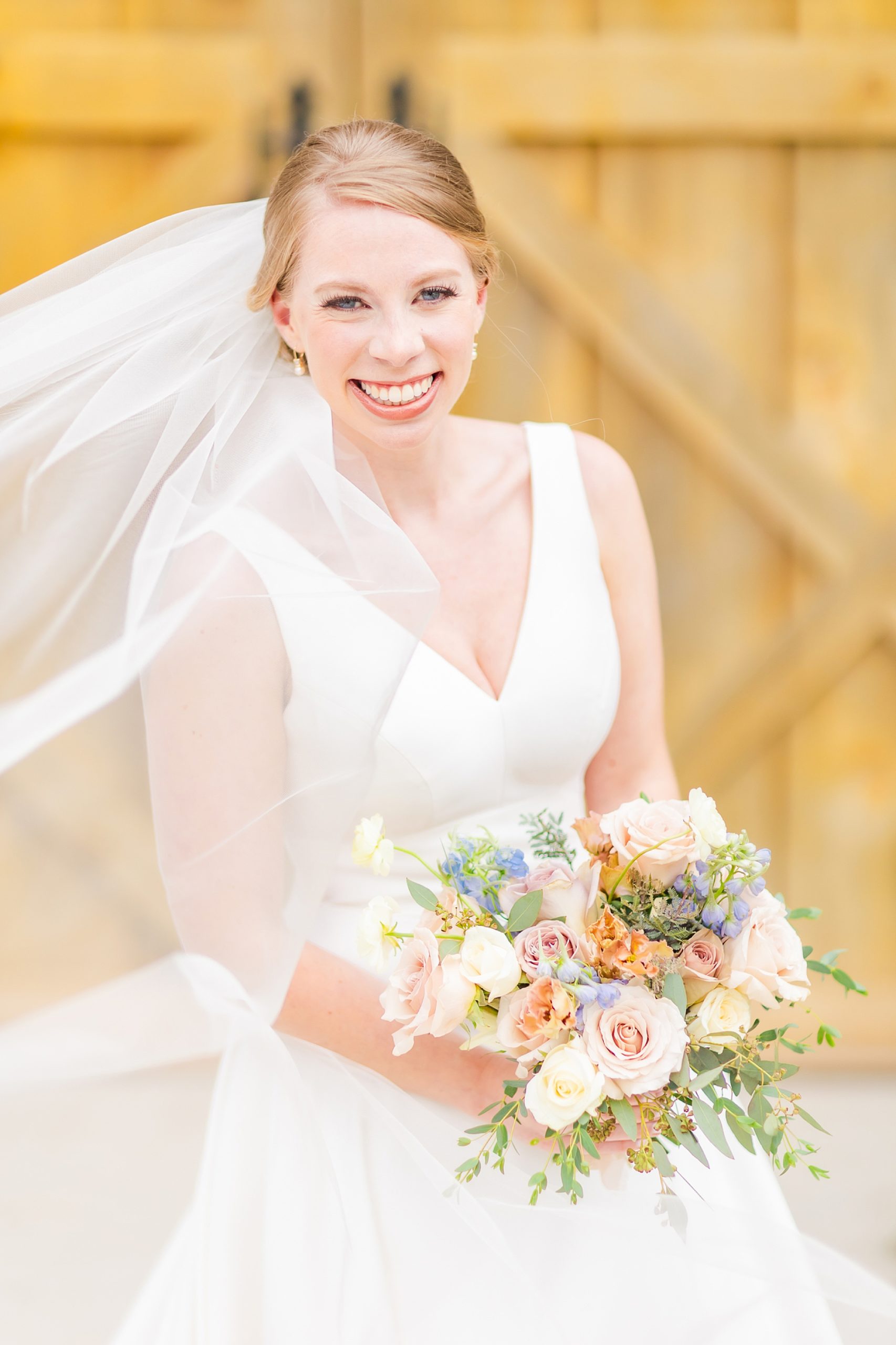 bride grins holding bouquet of pastel flowers at Old Homeplace Vineyard