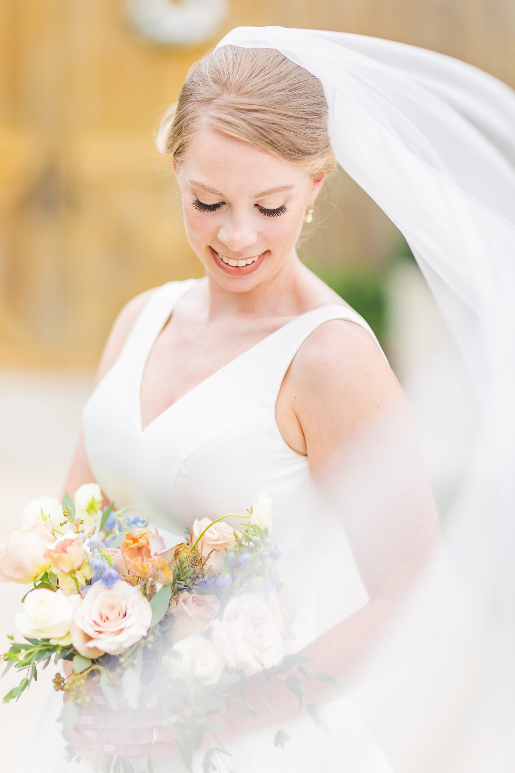 bride smiles down at bouquet during summer bridal portraits in Winston-Salem