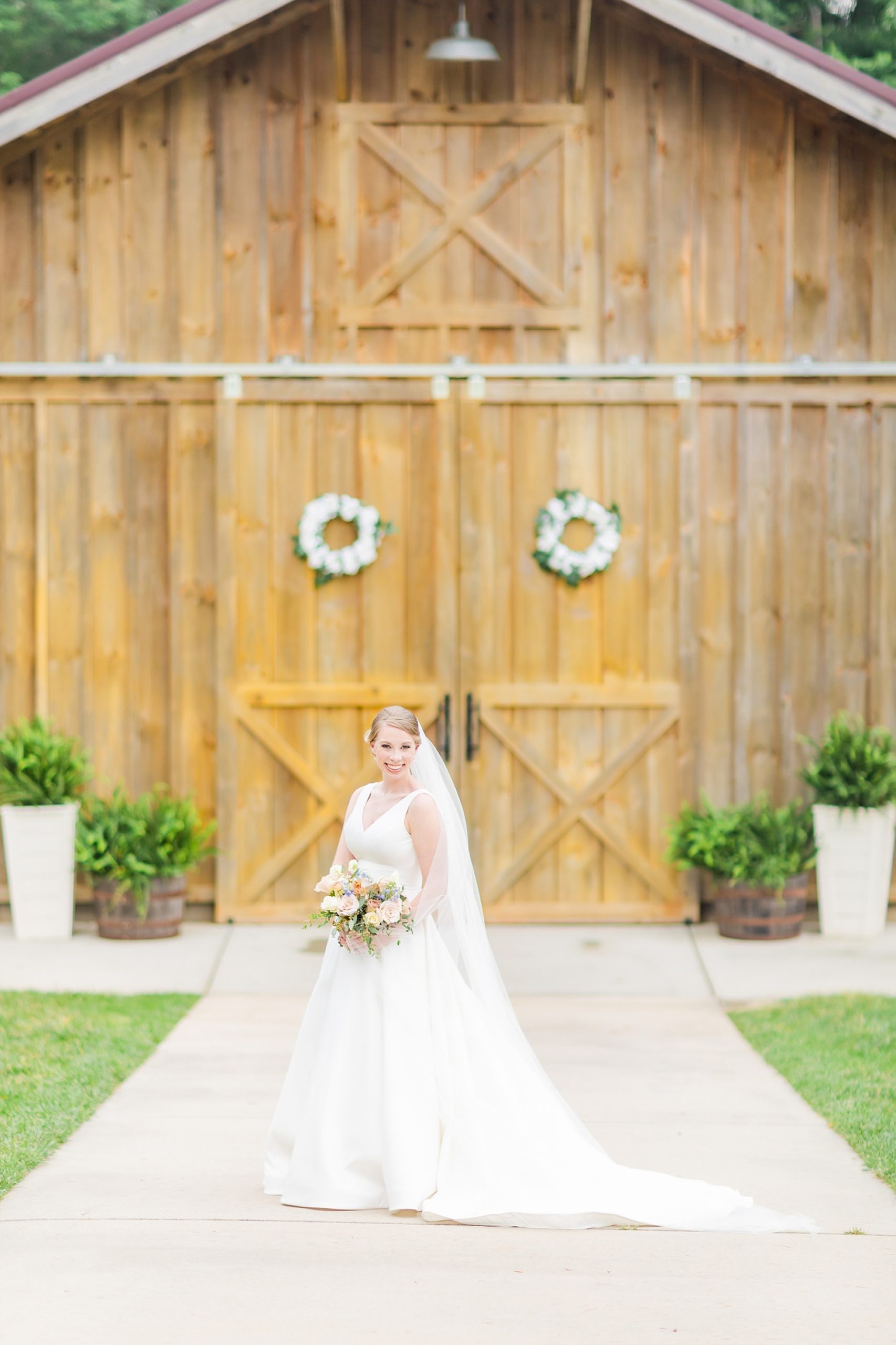 bride smiles outside wooden doors at Old Homeplace Vineyard