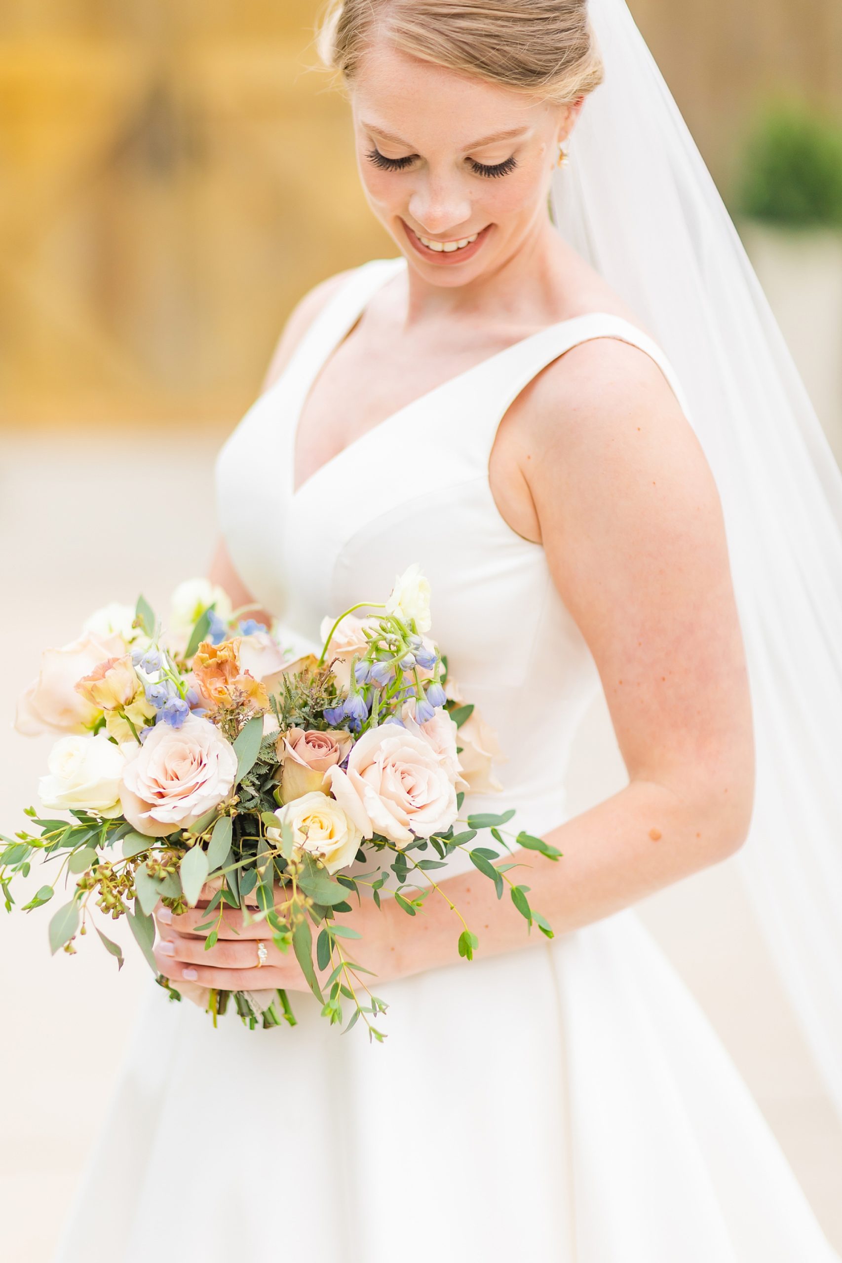 bride smiles down at pastel bouquet during bridal portraits with Charlotte wedding photographer Morgan Amanda Photography