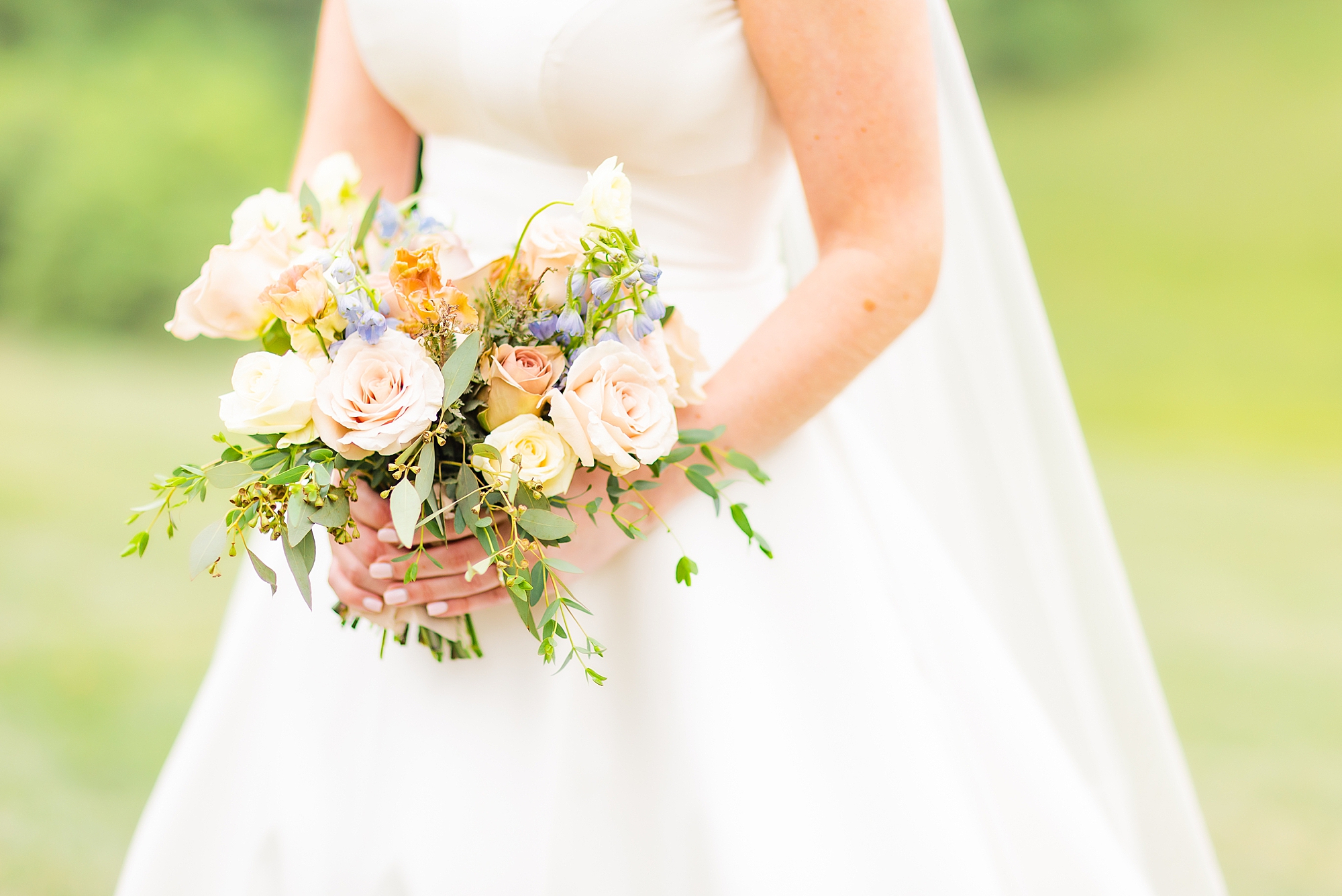 bride holds bouquet of light colored flowers