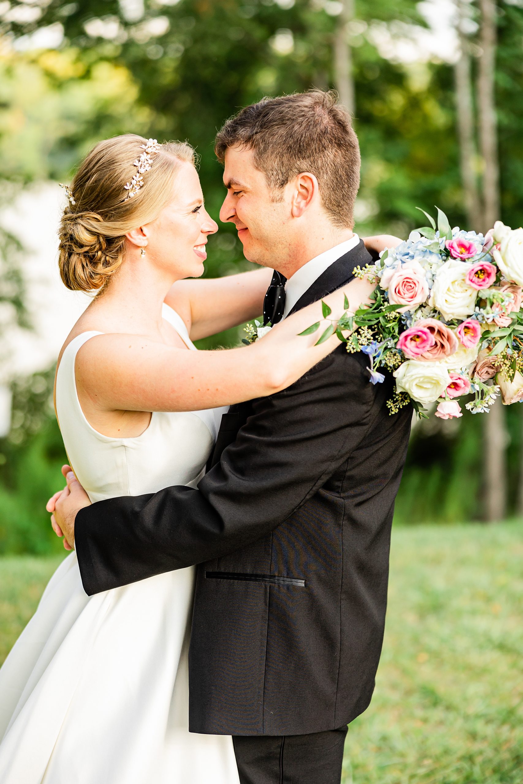 couple hugs facing each other with bride's bouquet behind groom's shoulders