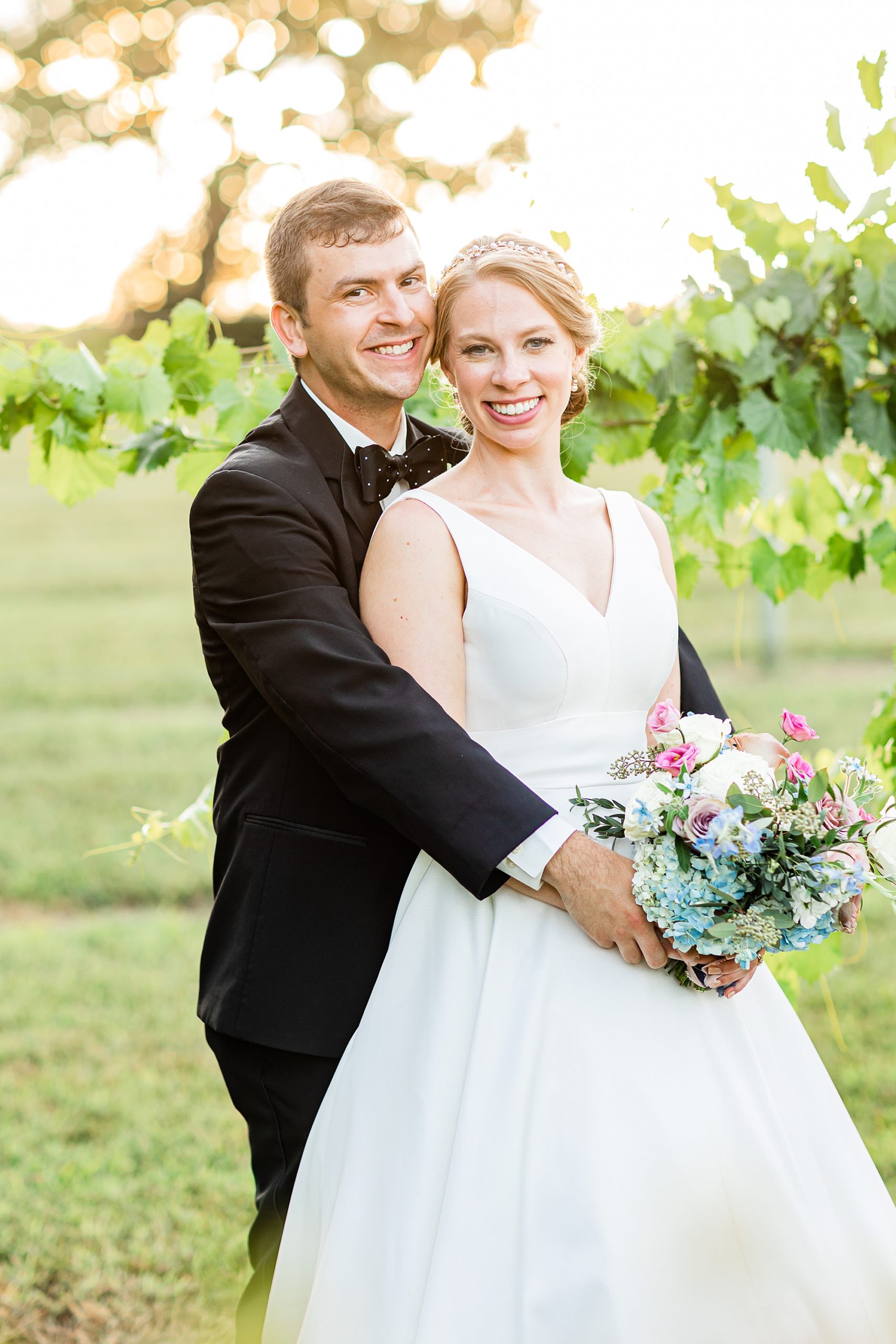 groom hugs bride from behind during portraits at Old Homeplace Vineyard