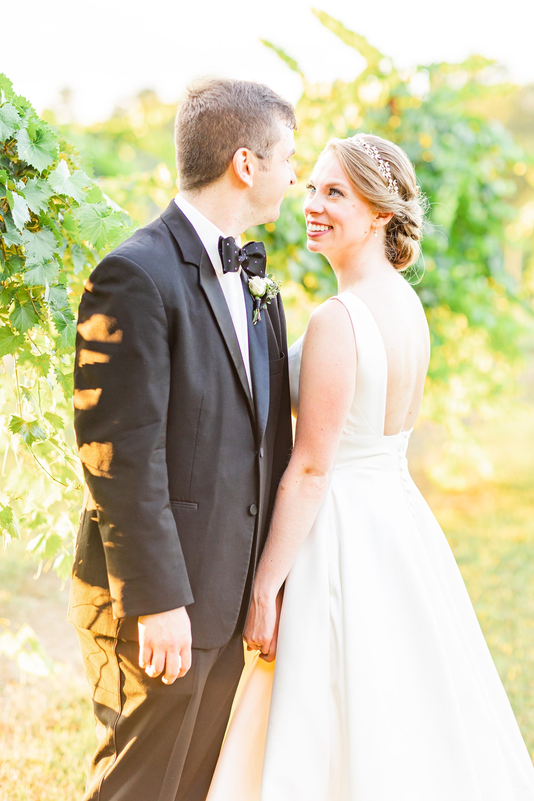 bride smiles up at groom during photos in vines