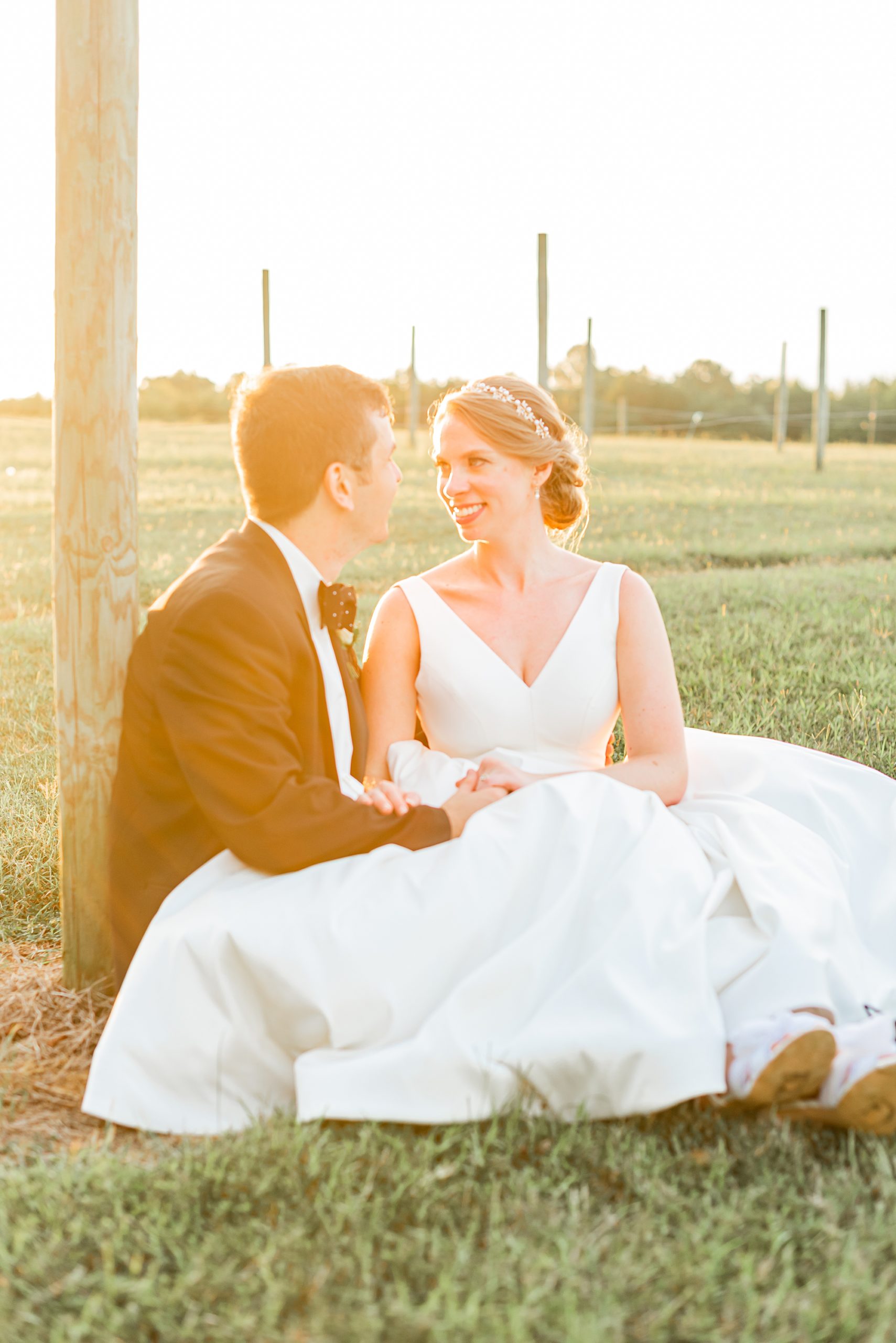 bride sits with groom by wooden pole at Old Homeplace Vineyard