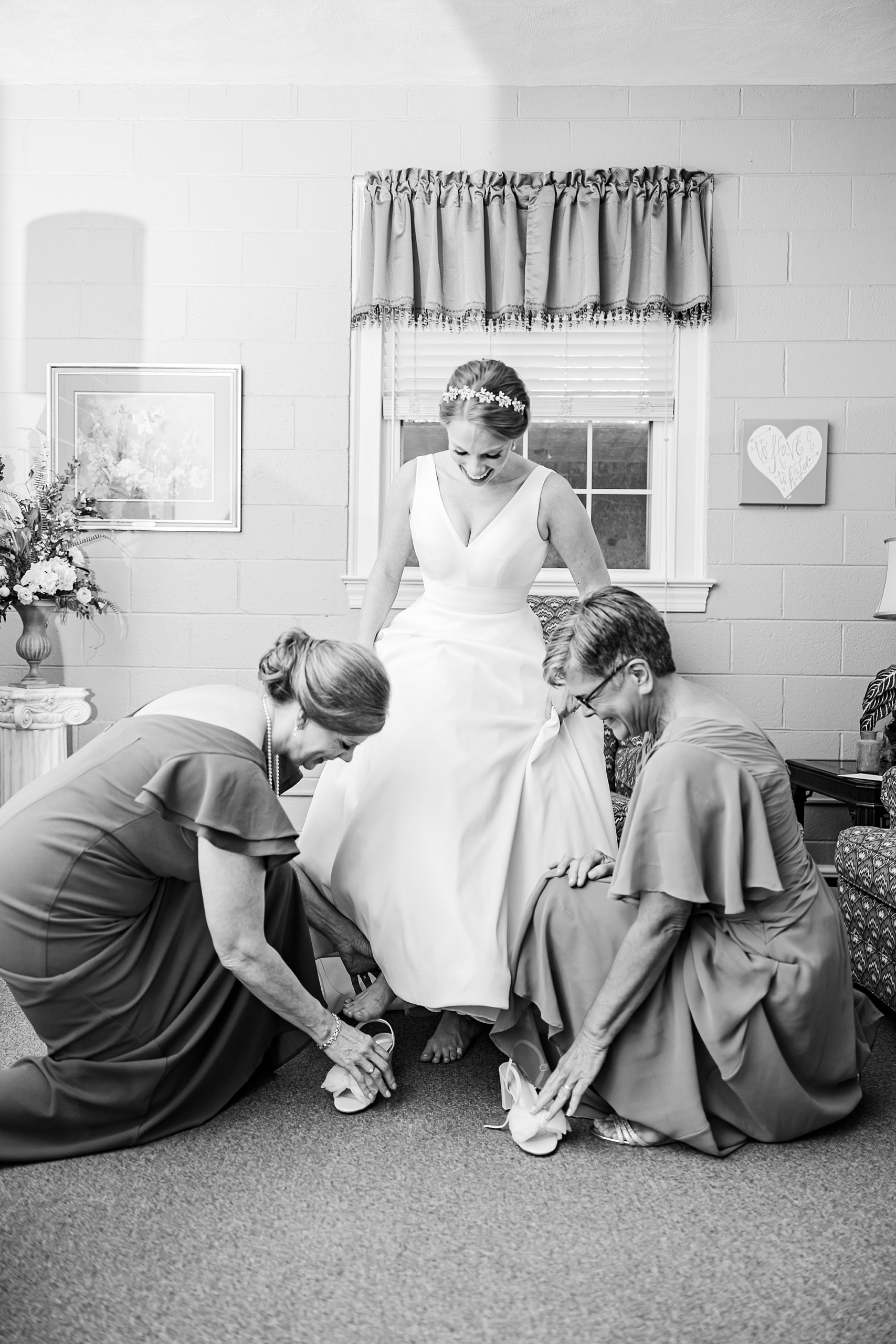 bridesmaids help bride into shoes on wedding morning 