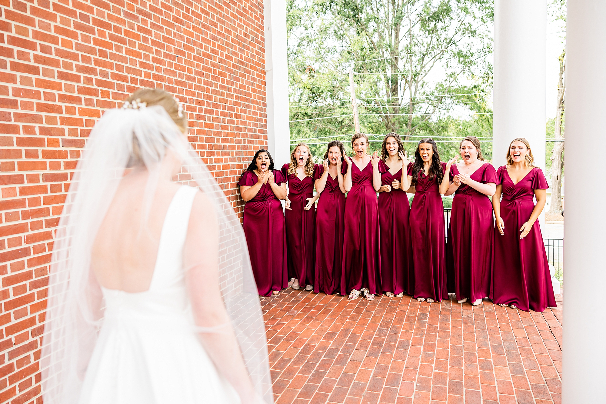 bridesmaids in red gowns have first look with bride