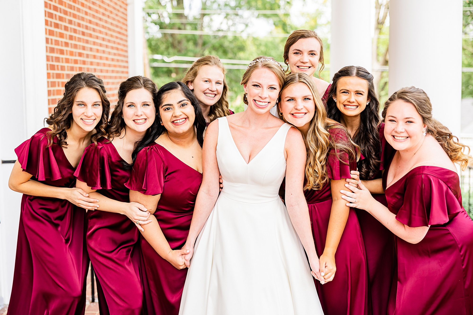 bride poses with bridesmaids in red gowns