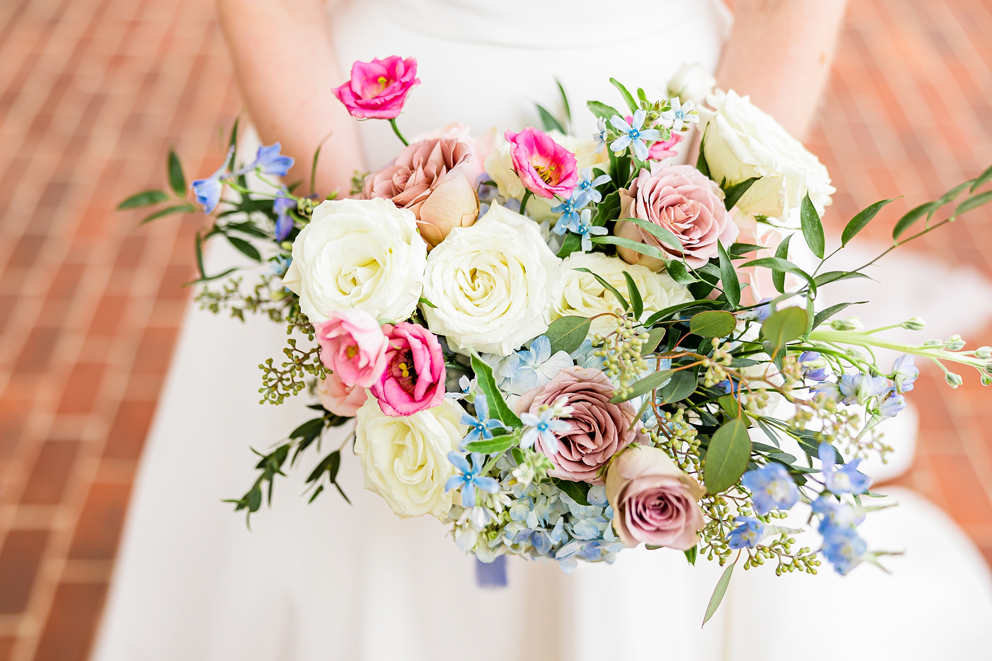 bride holds bouquet of pink, white, and blue flowers