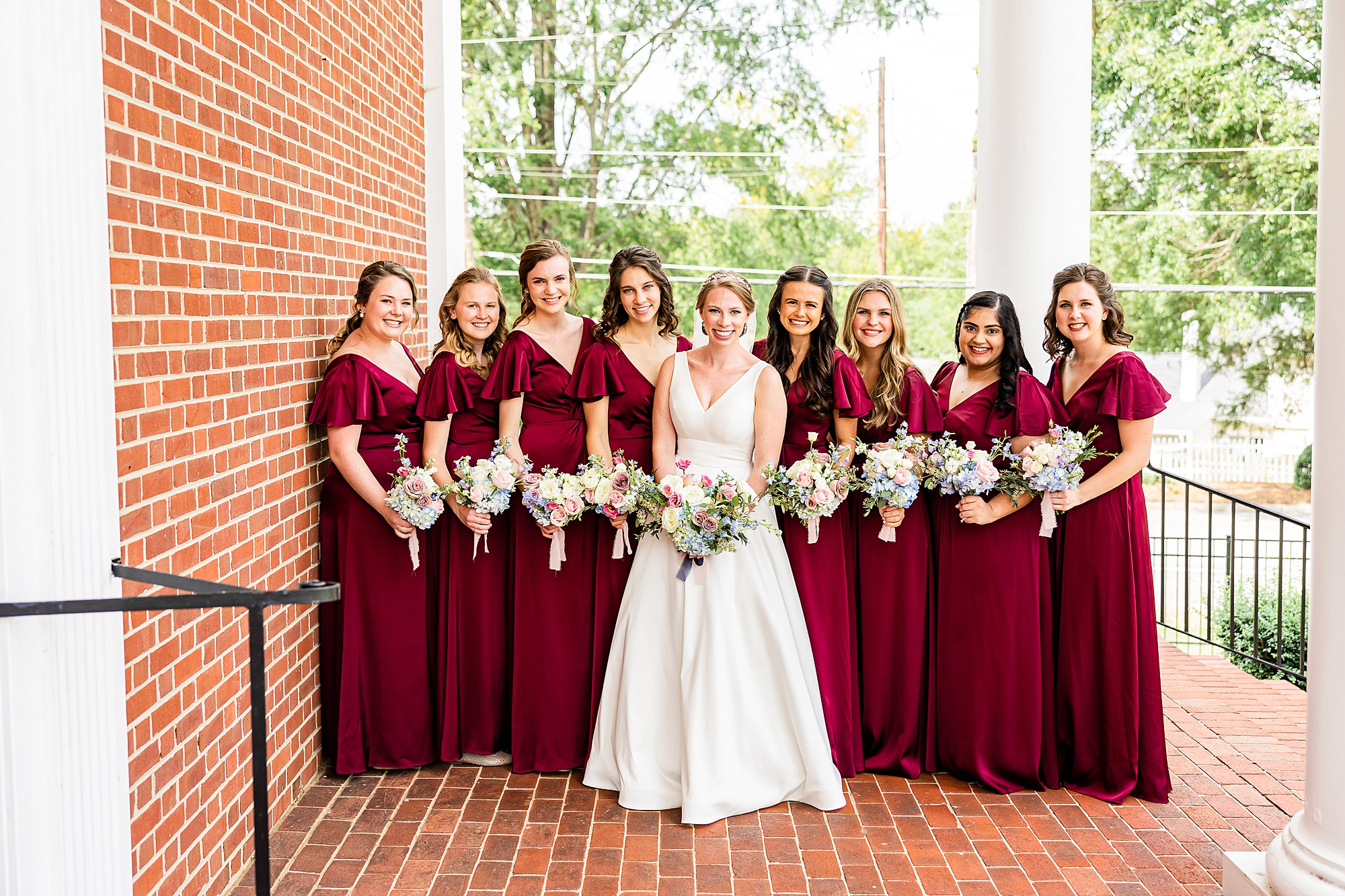 bride stands with bridesmaids in burgundy gowns at College Park Baptist Church