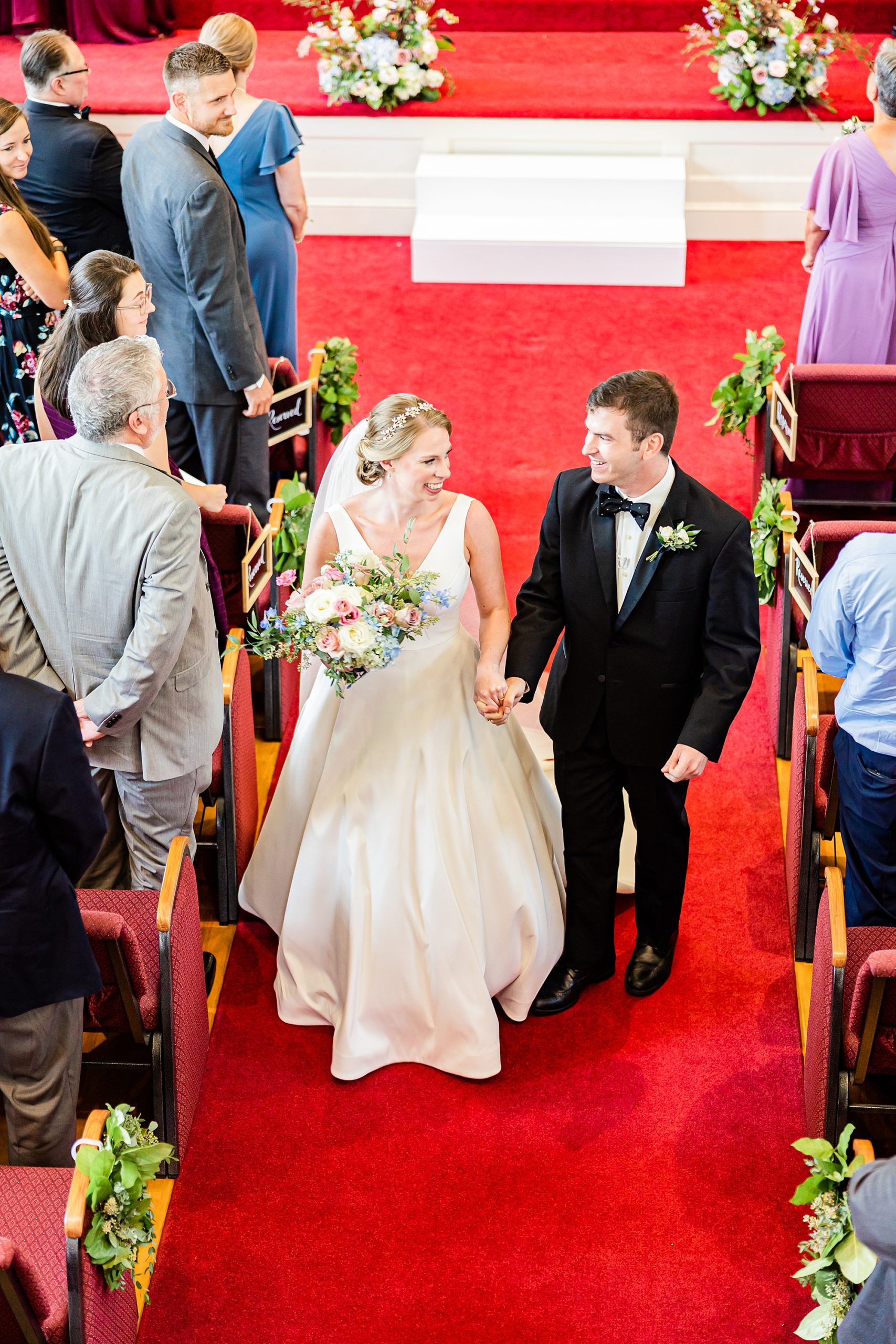 bride and groom hold hands walking up aisle after traditional wedding ceremony at College Park Baptist Church