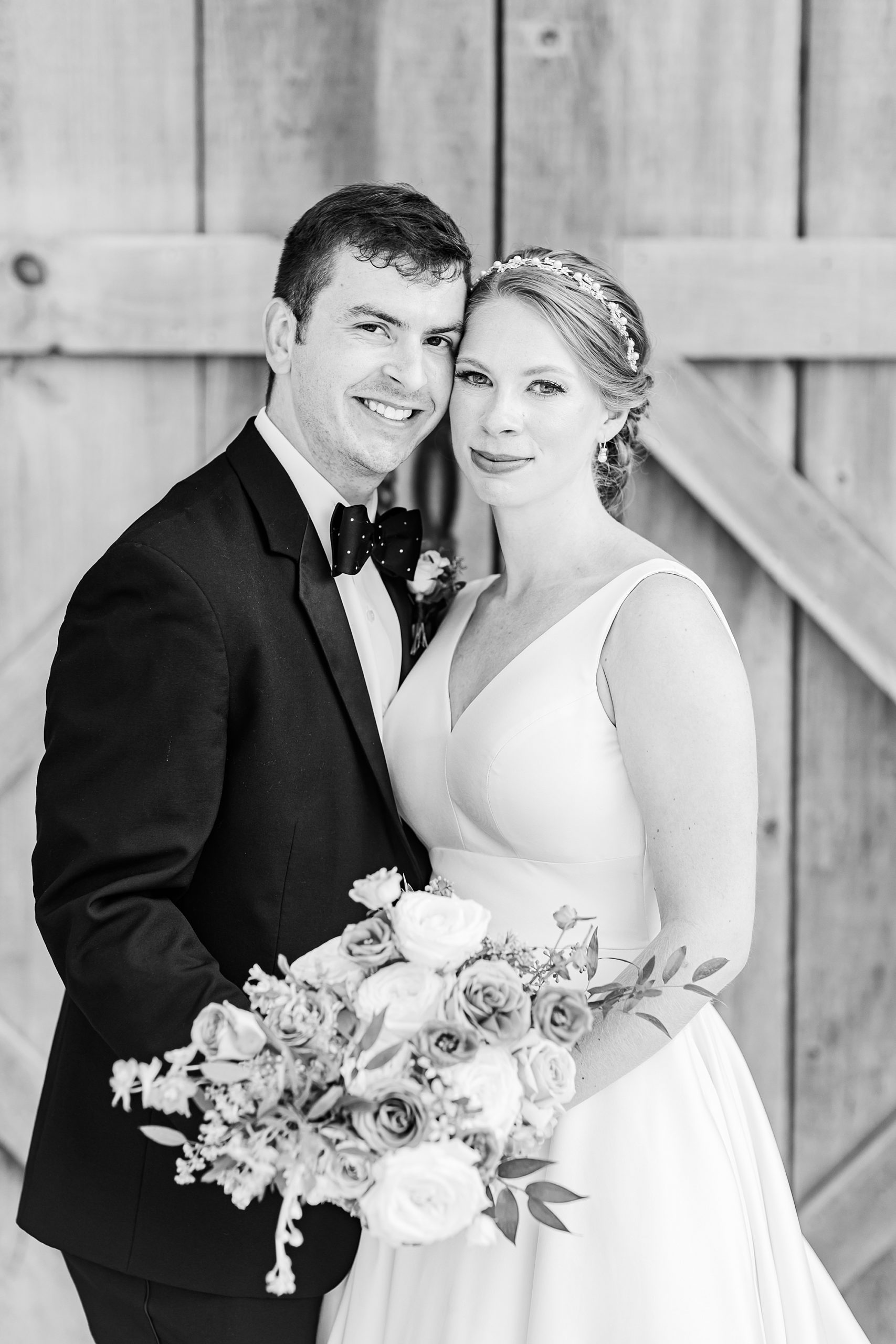 newlyweds stand outside barn door at Old Homeplace Vineyard