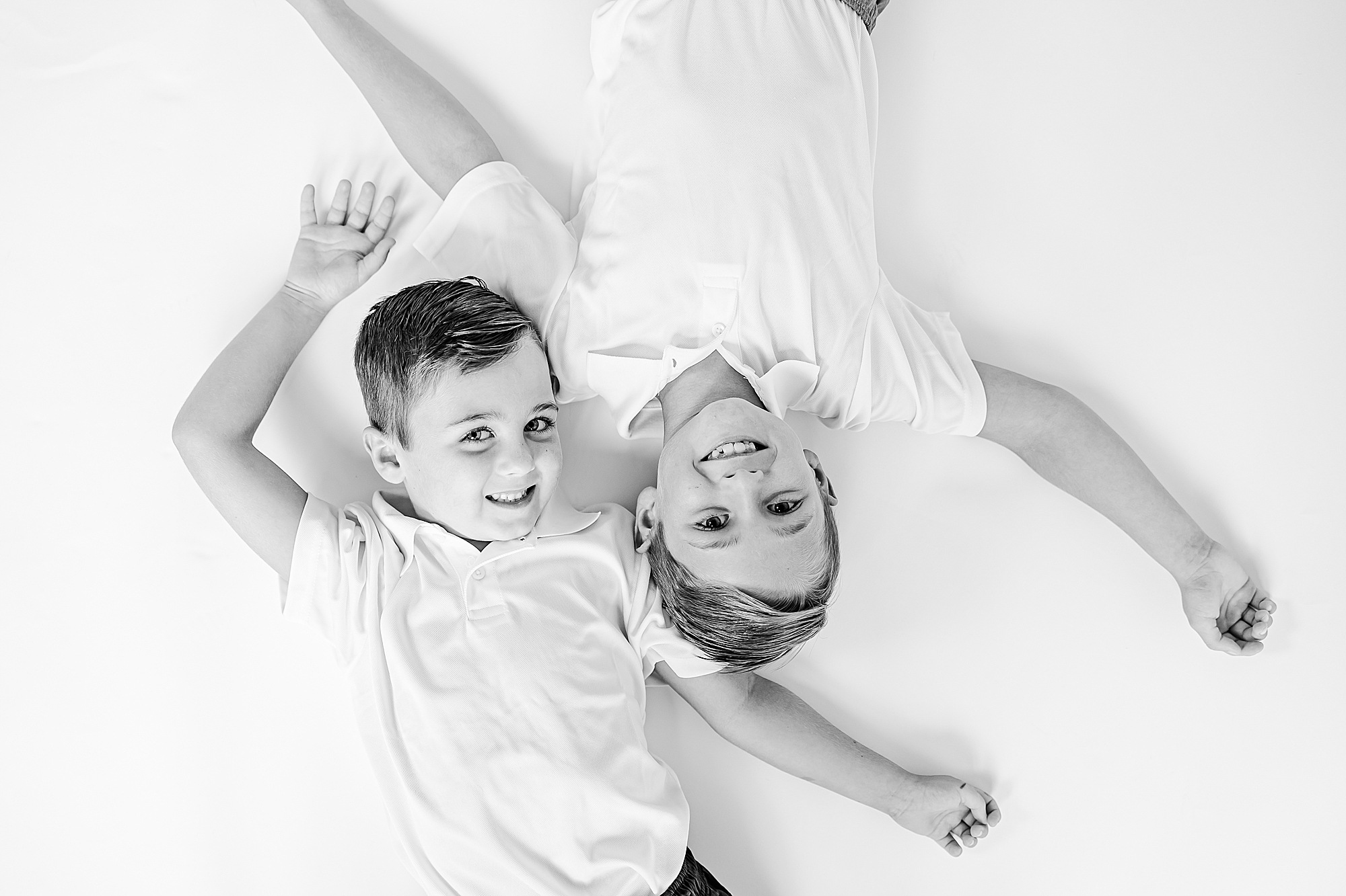 brothers lay on white studio backdrop during studio personality portraits