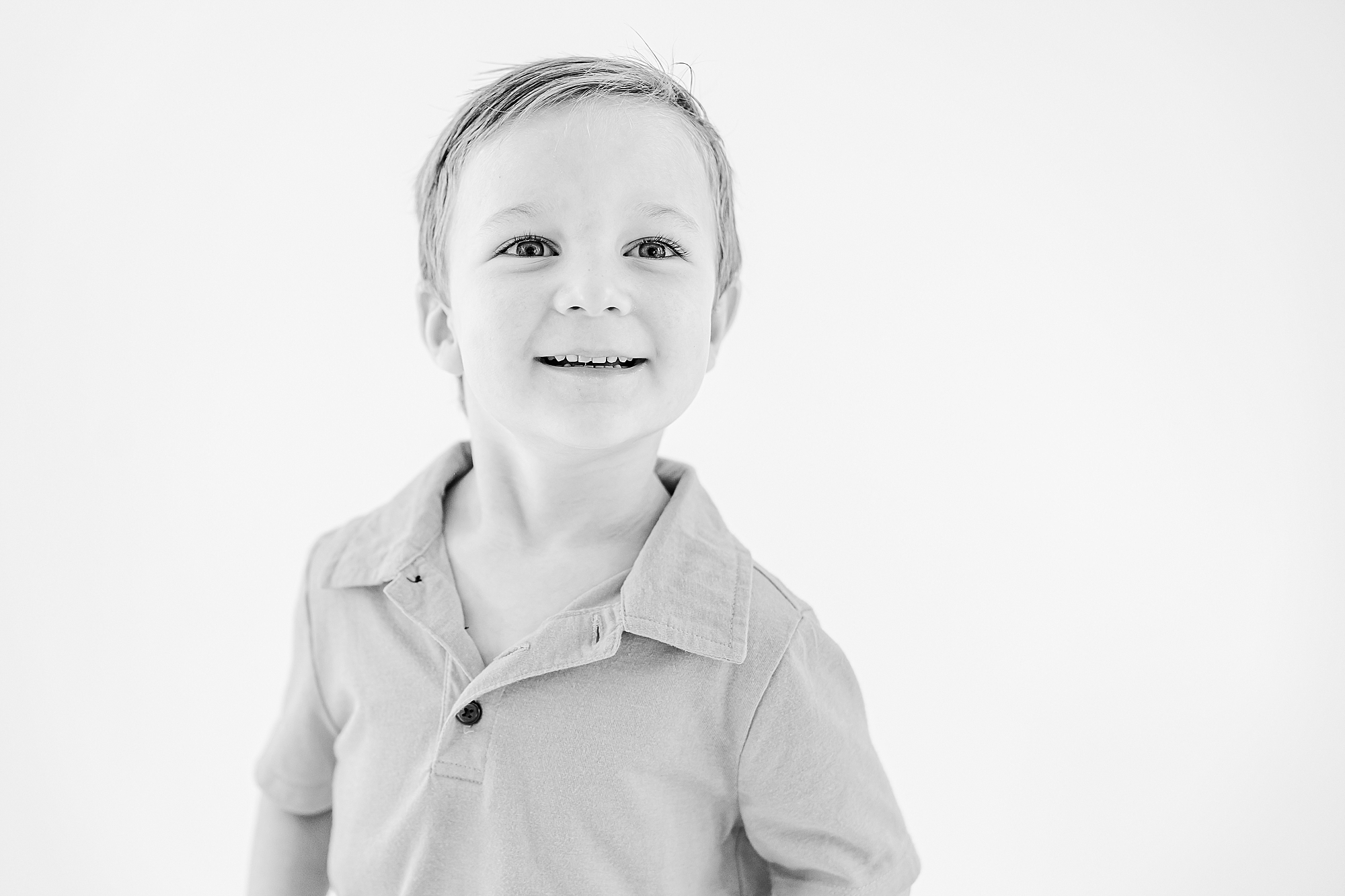 boy in polo shirt smiles during studio personality portraits