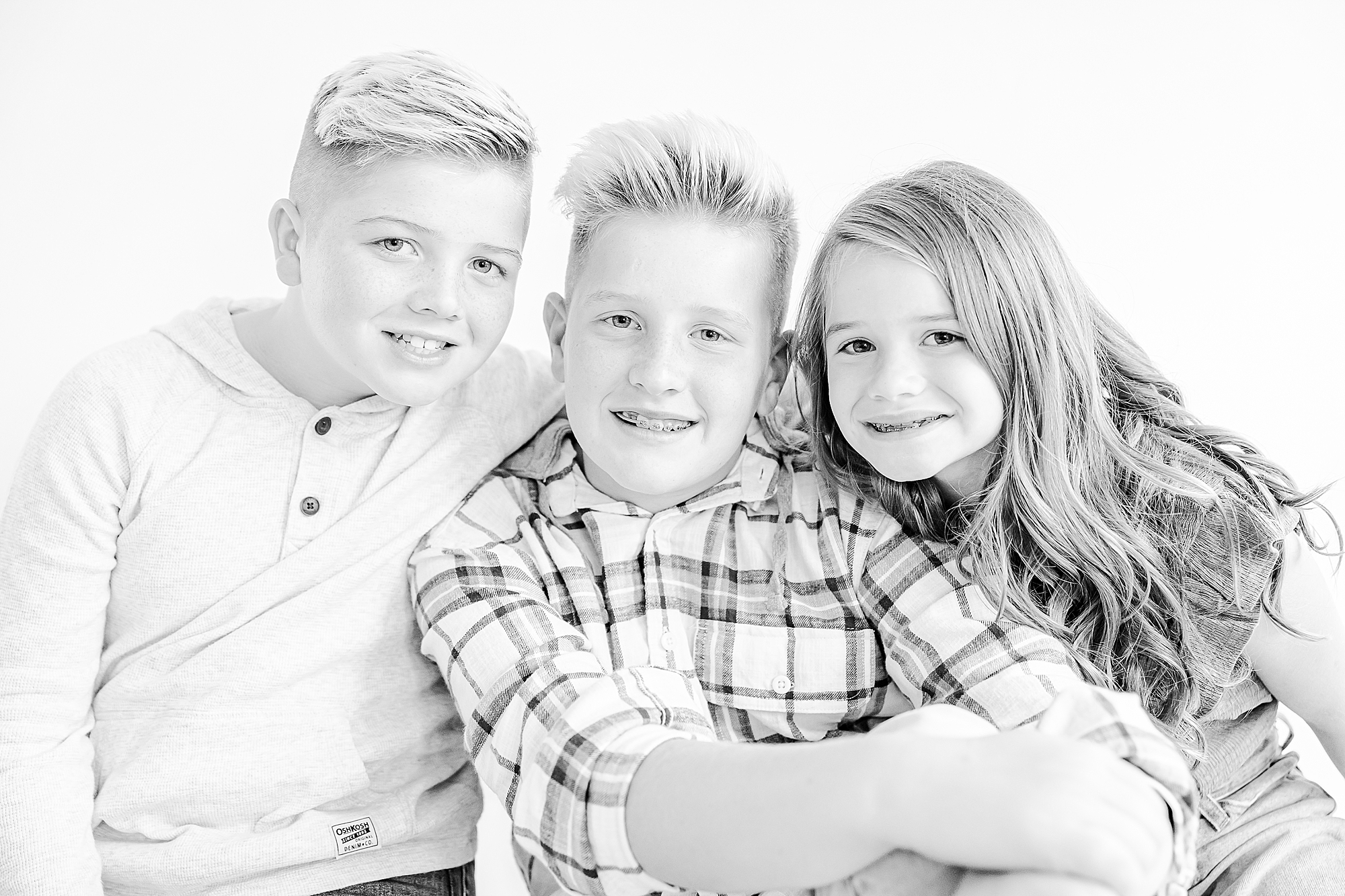 three siblings hug together during black and white studio personality portraits