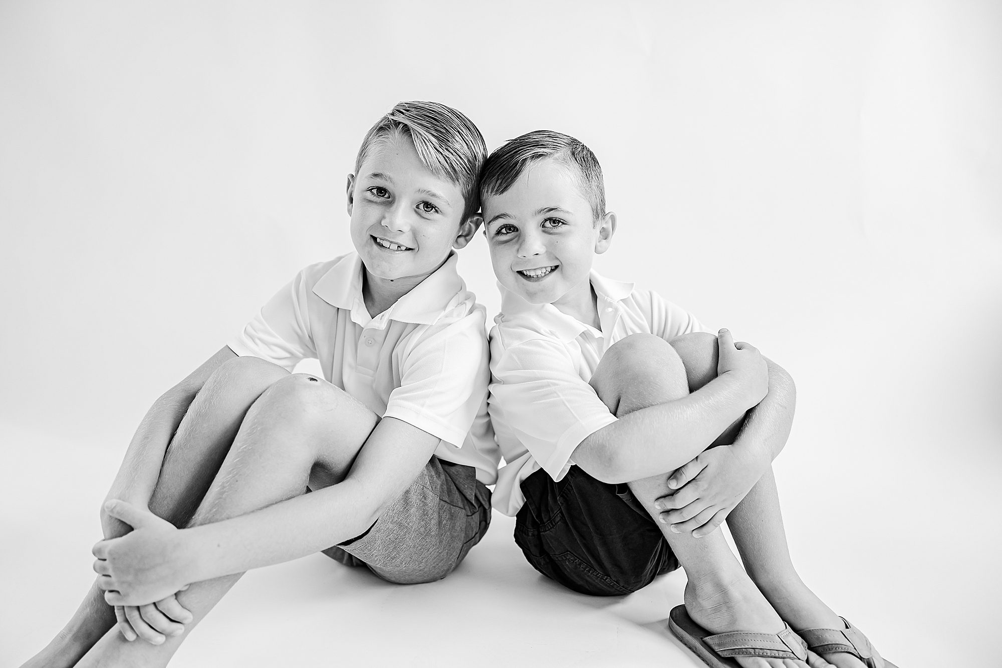 two boys sit back to back during studio personality portraits