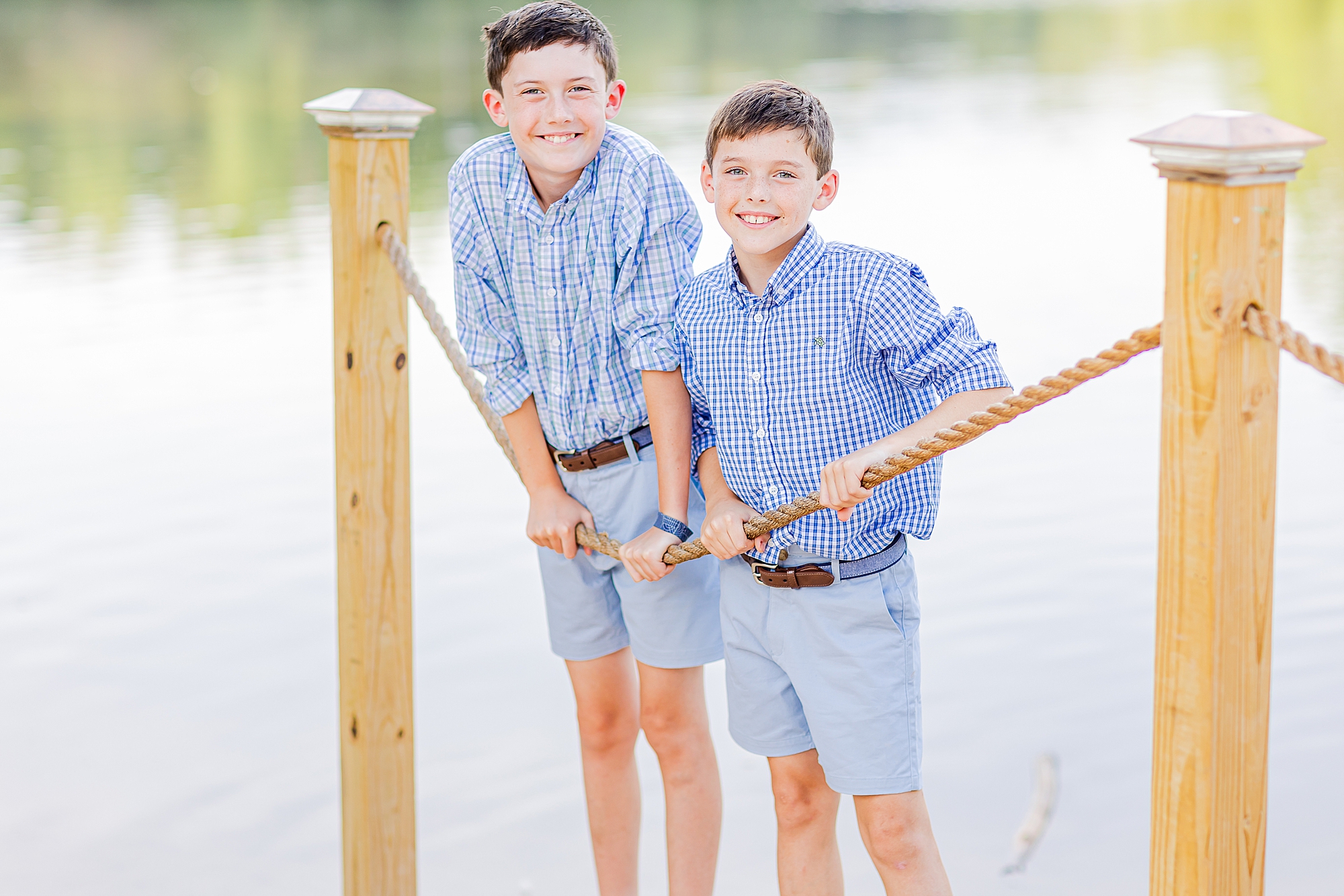 boys lean against rope during lakefront family portraits in Charlotte 