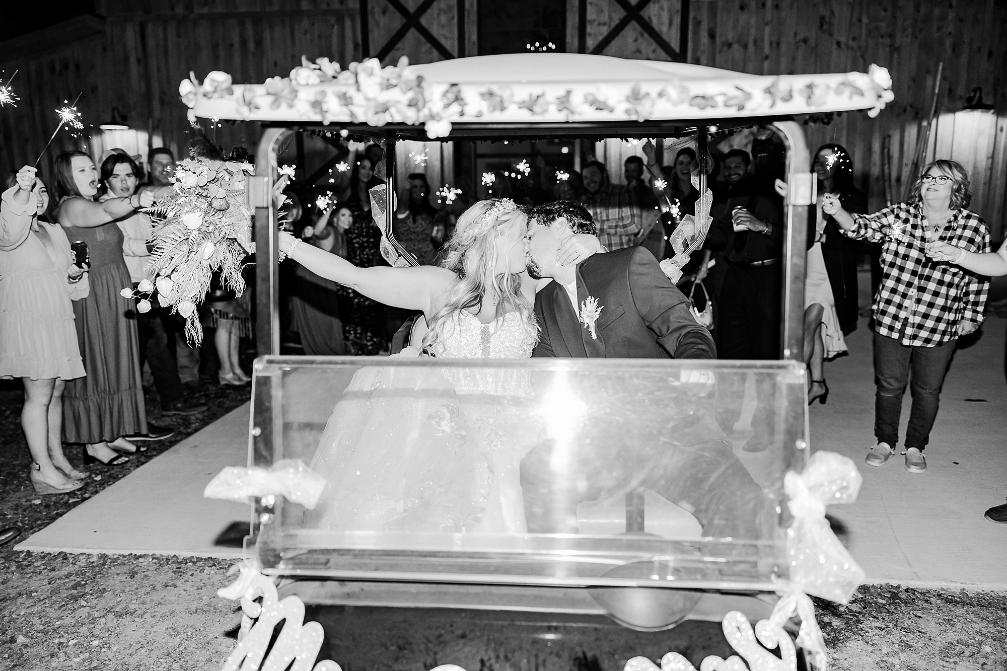bride and groom kiss in golf cart leaving Belmont NC wedding reception in barn