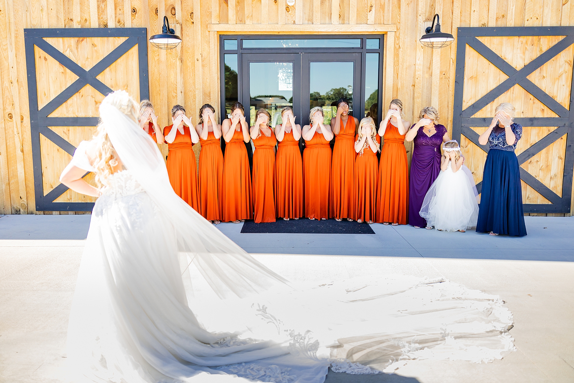 bridesmaids in burnt orange cover eyes for first look with bride 