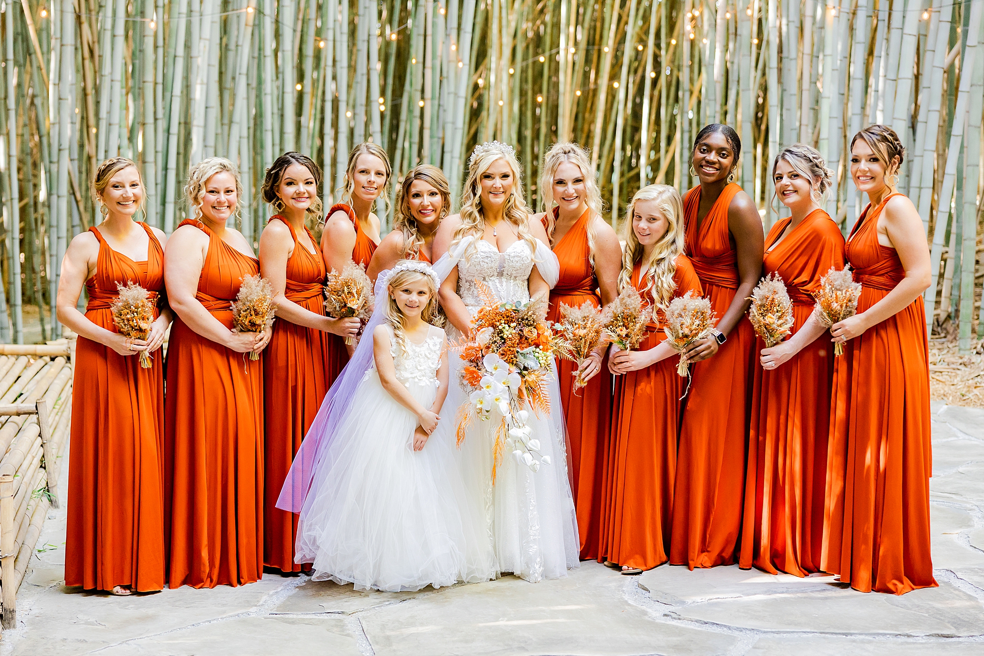 bride poses with bridesmaids in burnt orange gowns 
