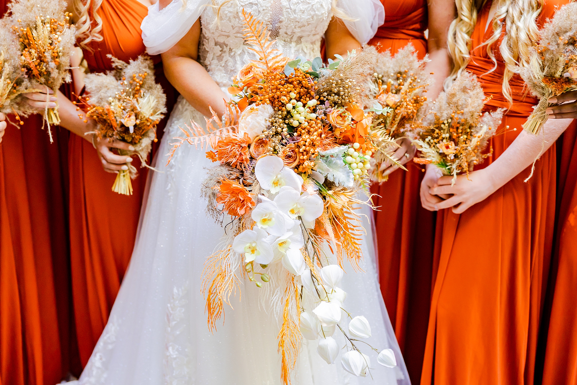 bride and bridesmaids hold wildflower bouquets with fall colors at Camelot Meadows