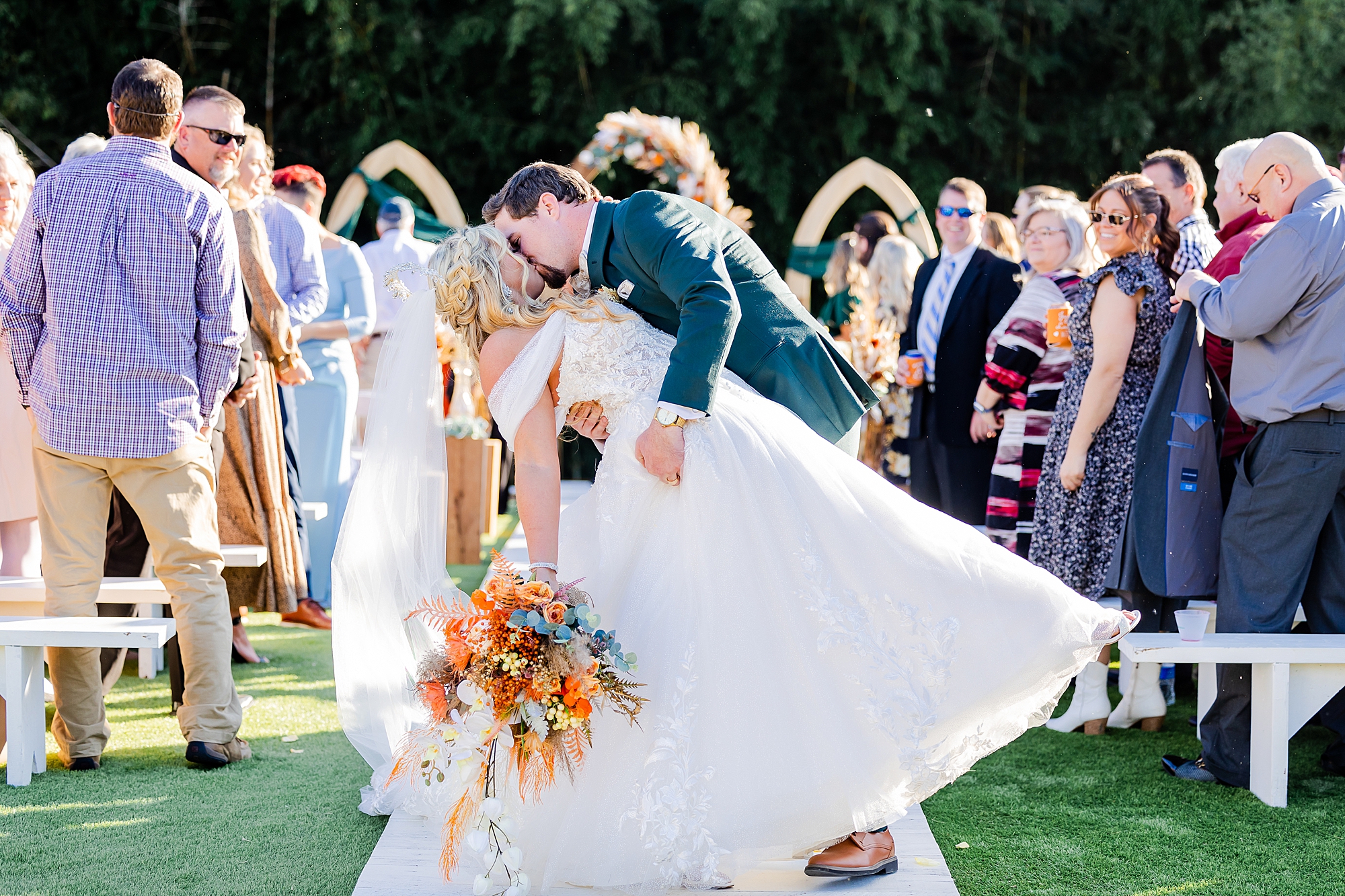 groom dips bride kissing her at end of aisle at Camelot Meadows