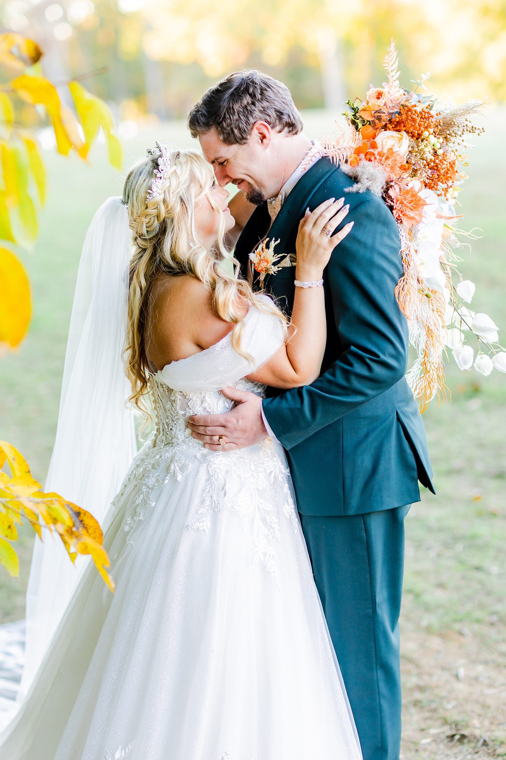 bride and groom hug by tree with yellow leaves at Camelot Meadows
