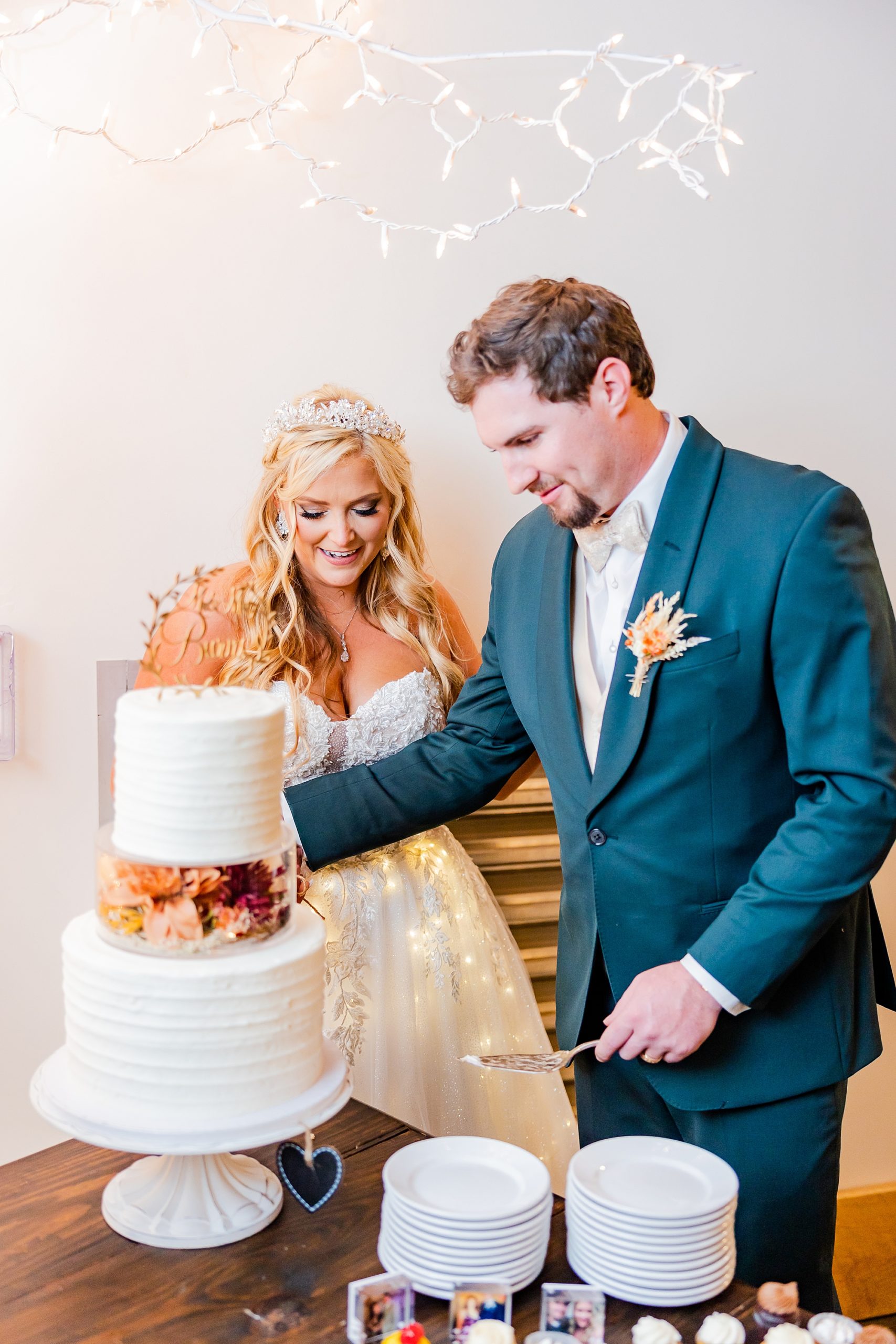 bride and groom cut wedding cake during Belmont NC wedding reception in barn