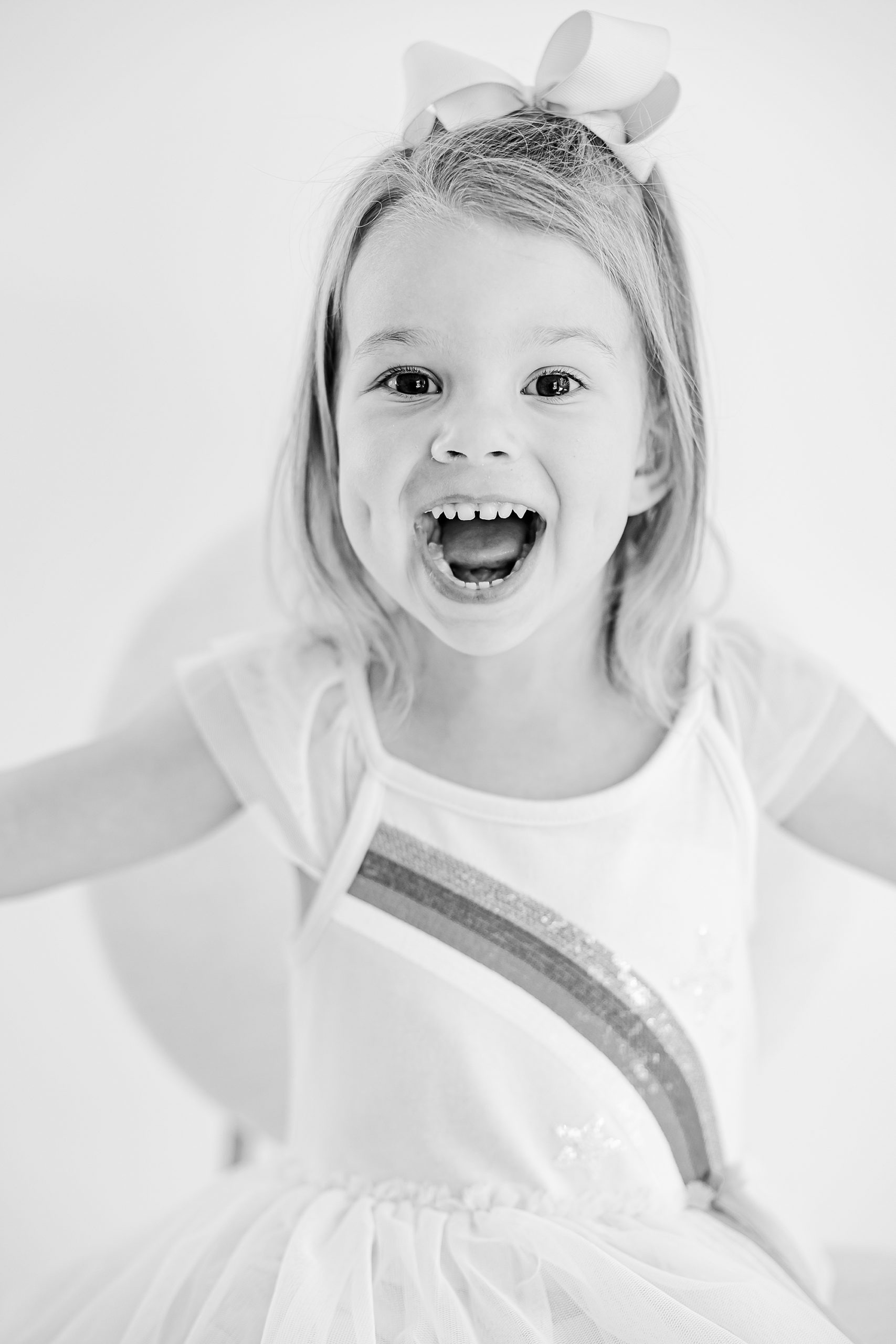 girl laughs sitting in chair during studio portraits
