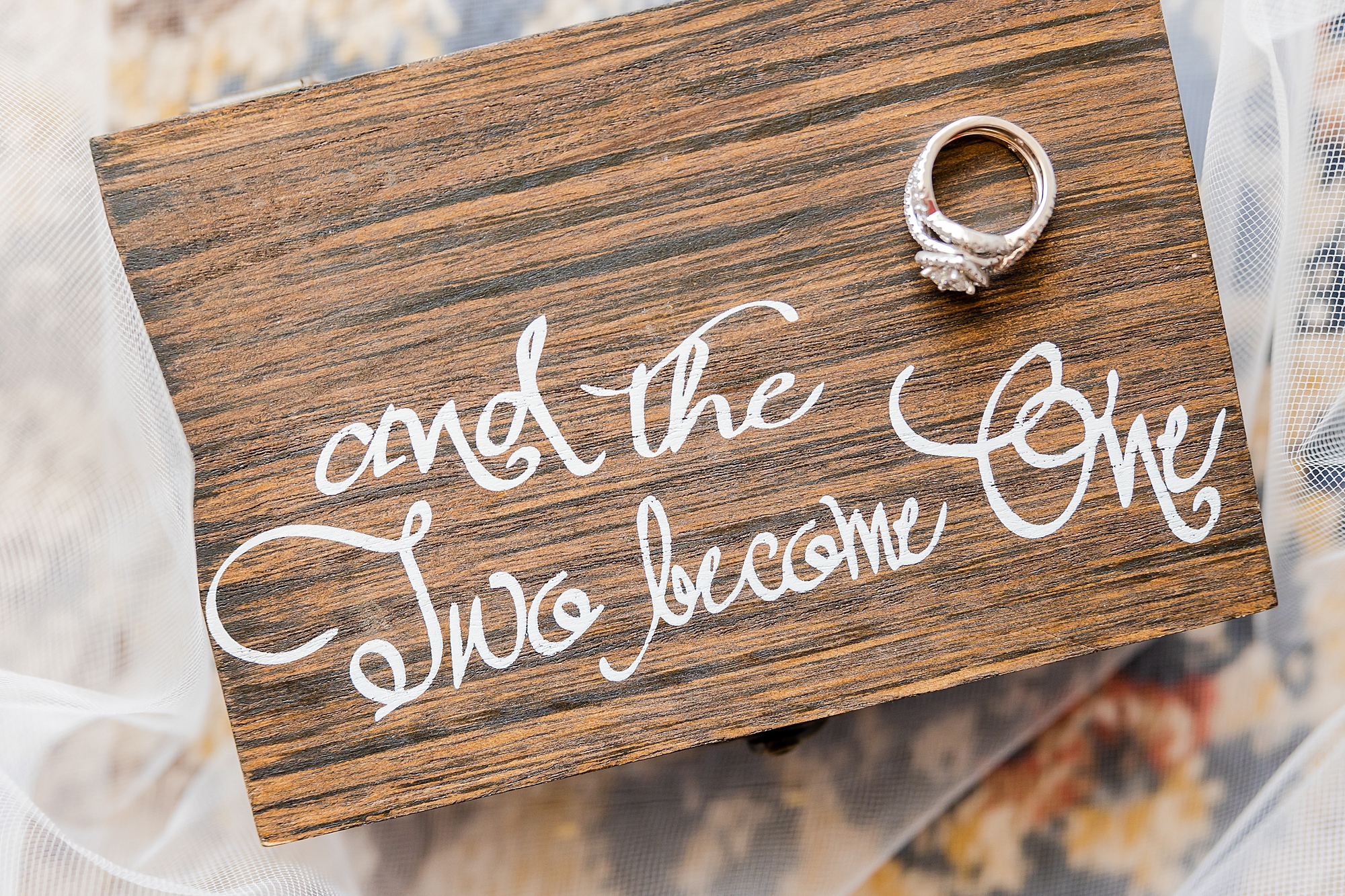 wedding rings rest on wooden sign before Charleston wedding