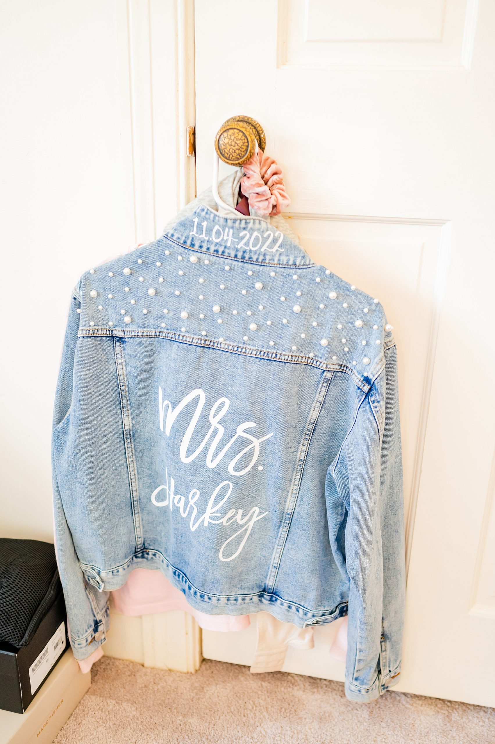 bride's custom jean jacket hangs on door knob