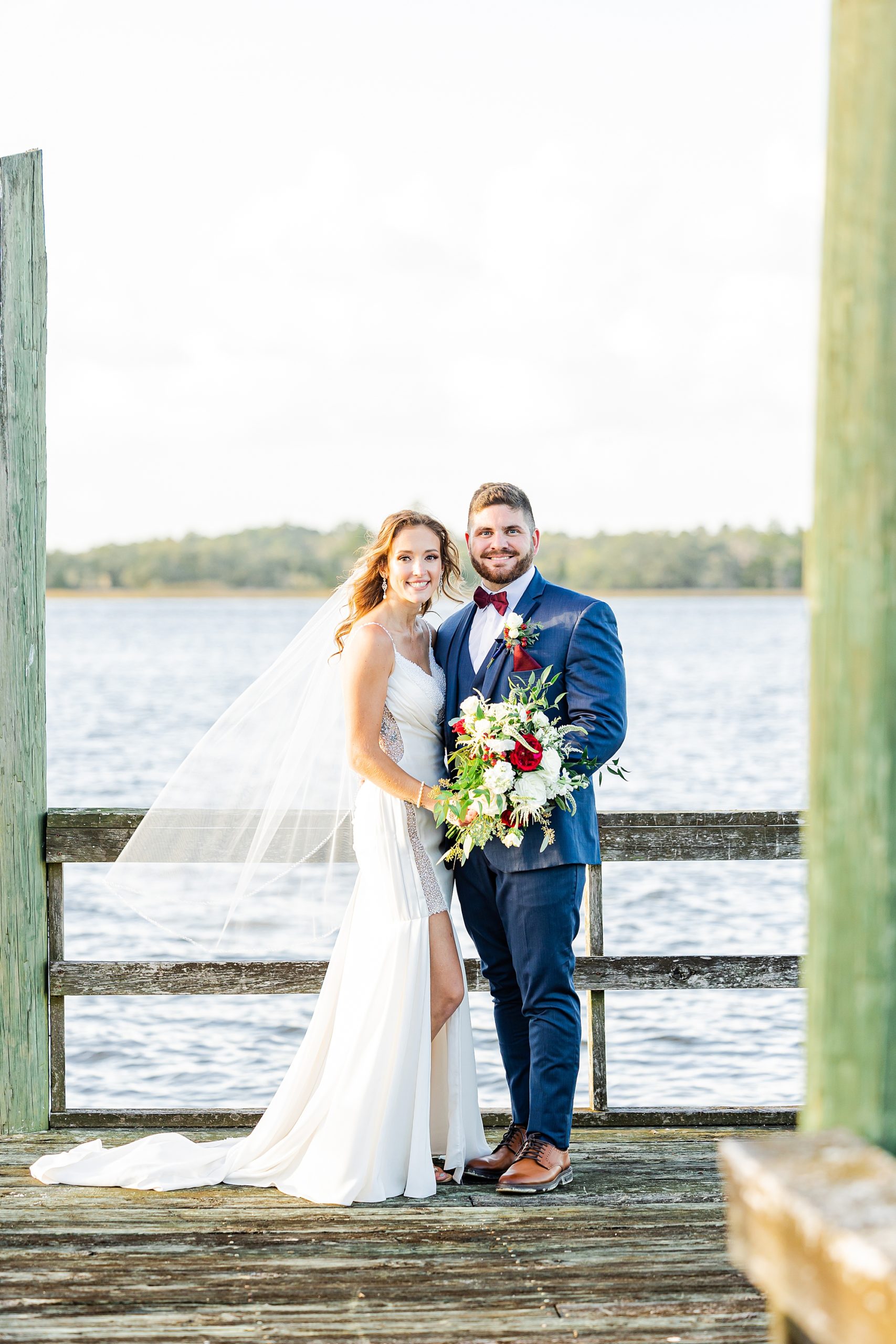 bride and groom pose on pier during John's Island wedding day