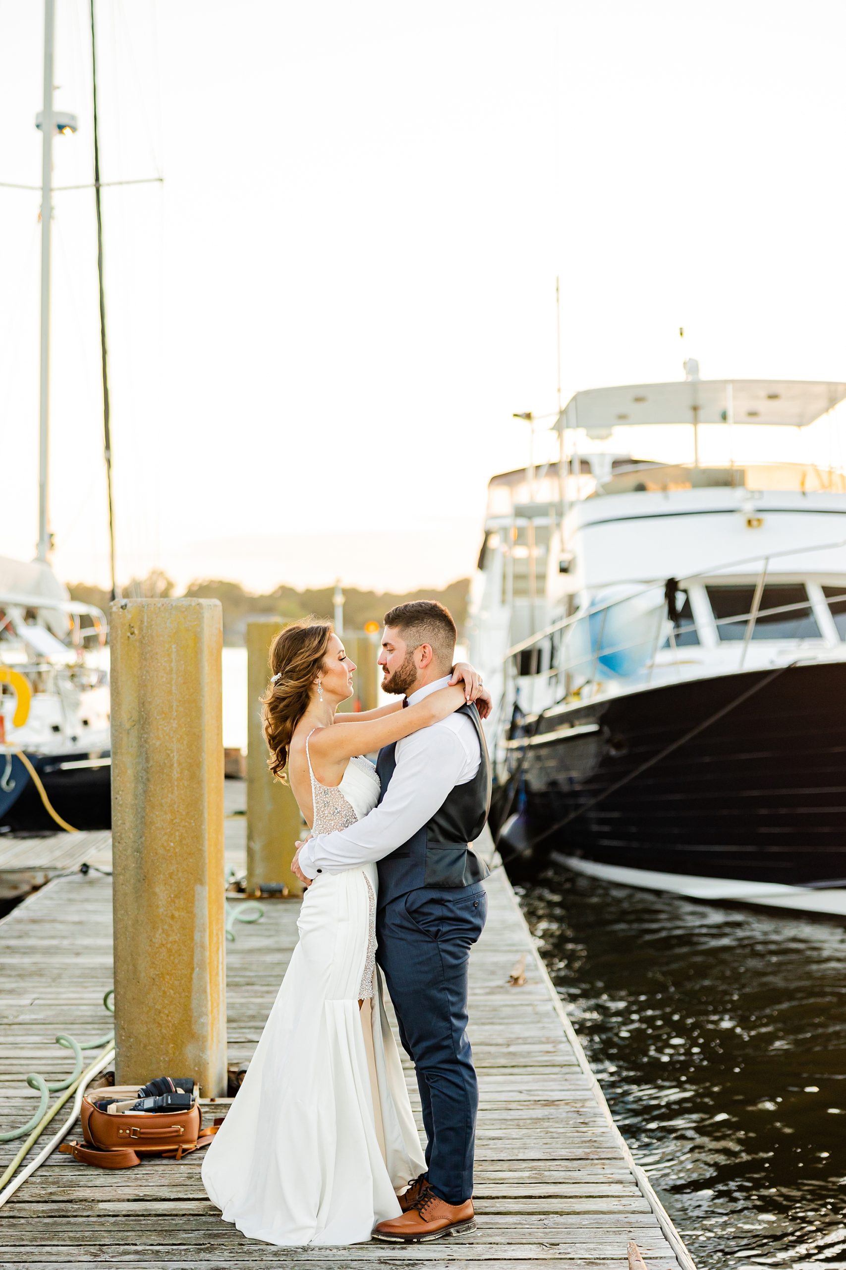 bride and groom hug on wooden pier by boat 