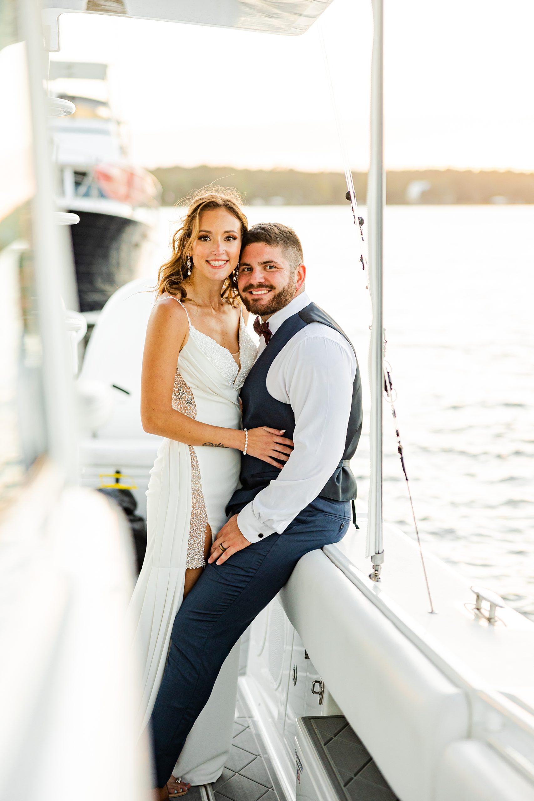 groom hugs bride between his legs on side of boat at John's Island 