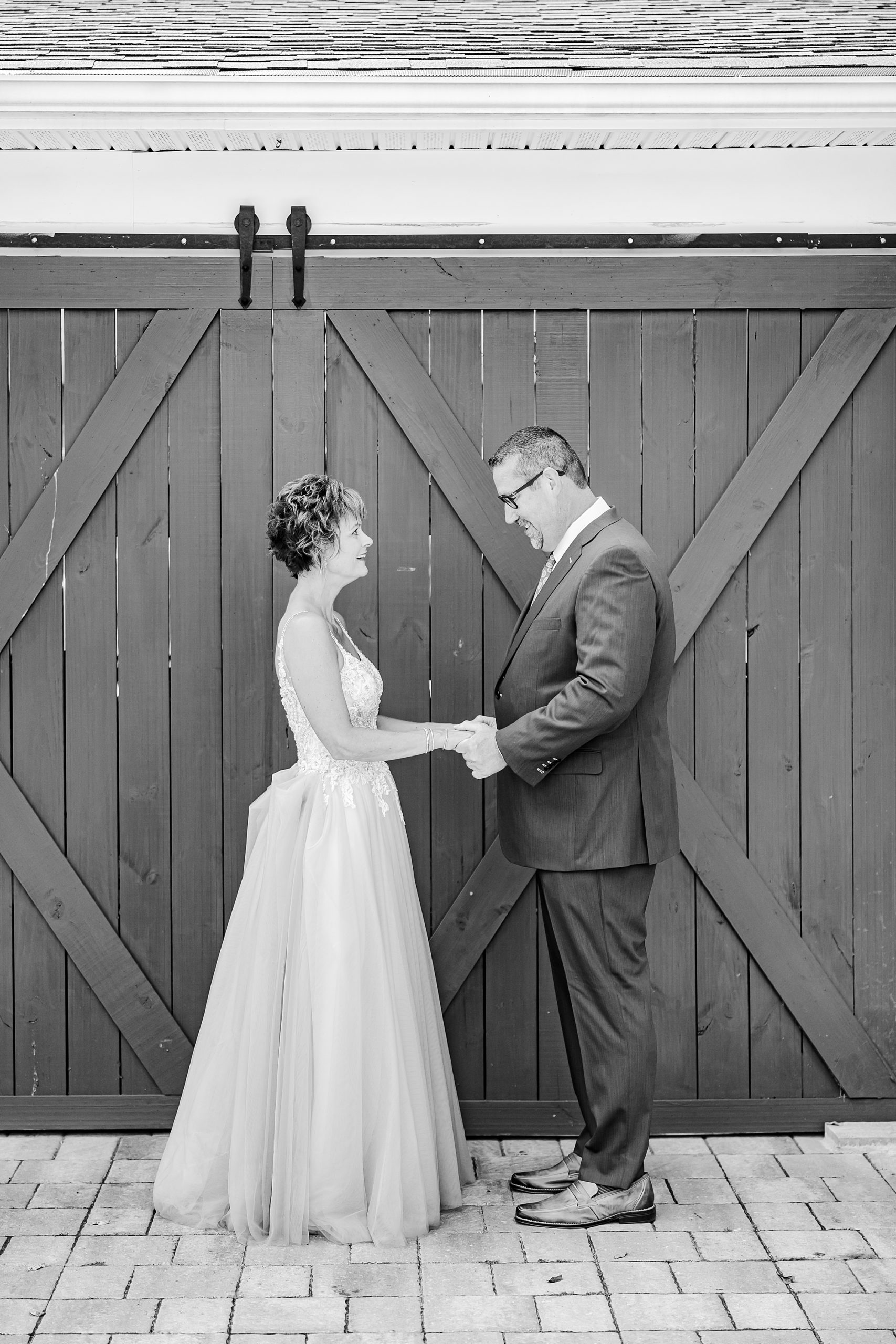 bride and groom hold hands by barn doors at Starclaire Recreation Club