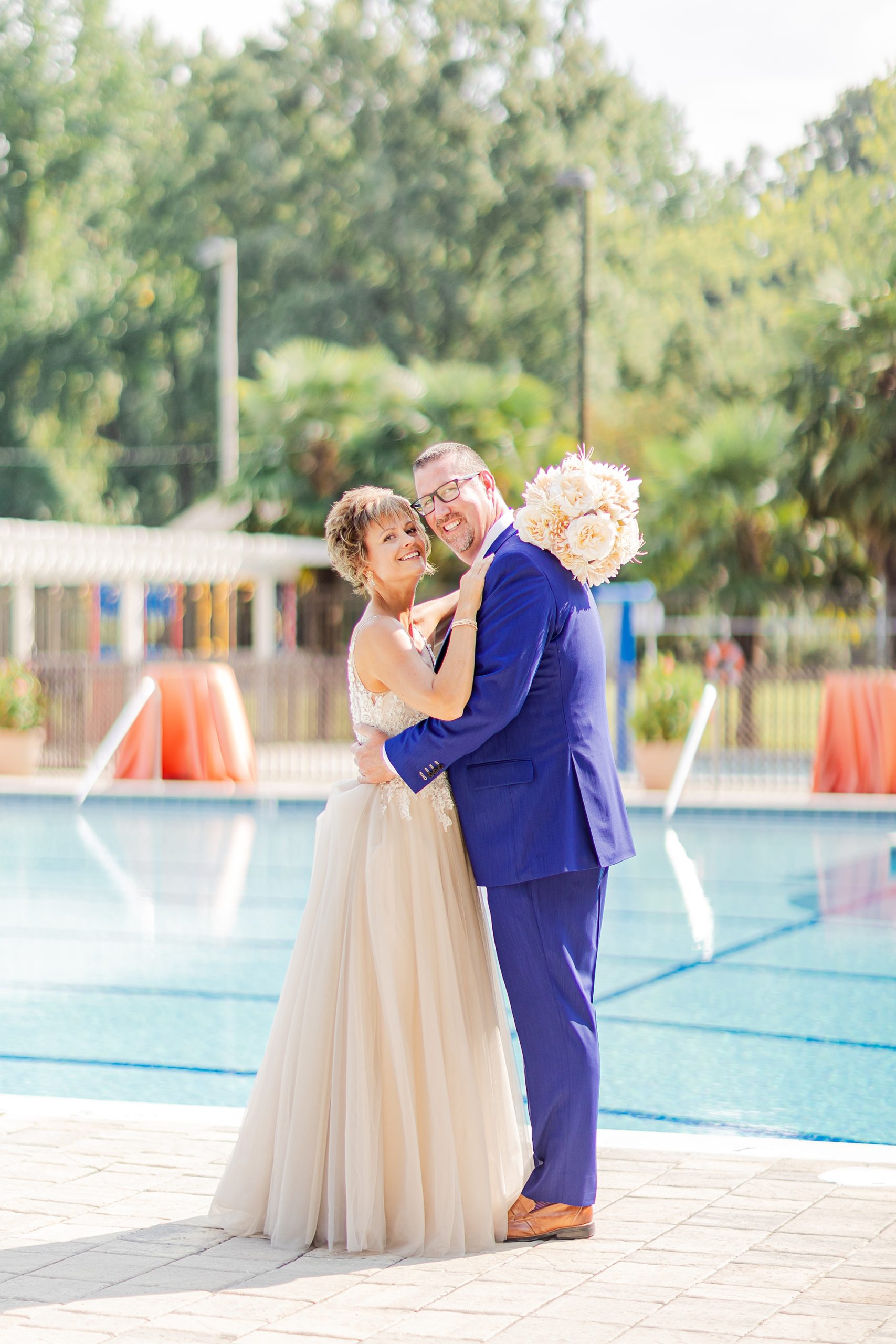 groom hugs bride during portraits by the pool at Starclaire Recreation Club