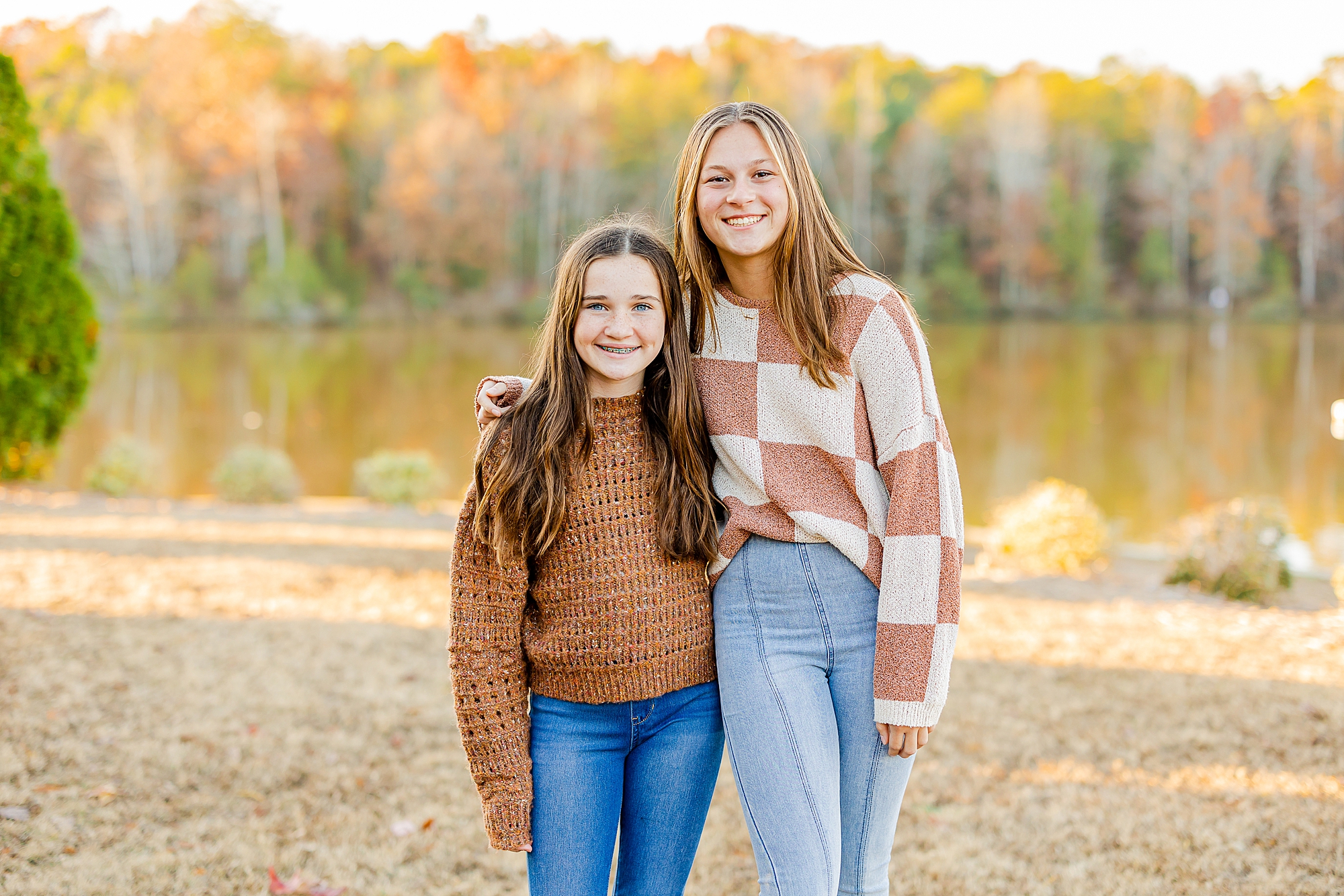 two sisters hug in brown sweaters near lake in Francis Beatty Park